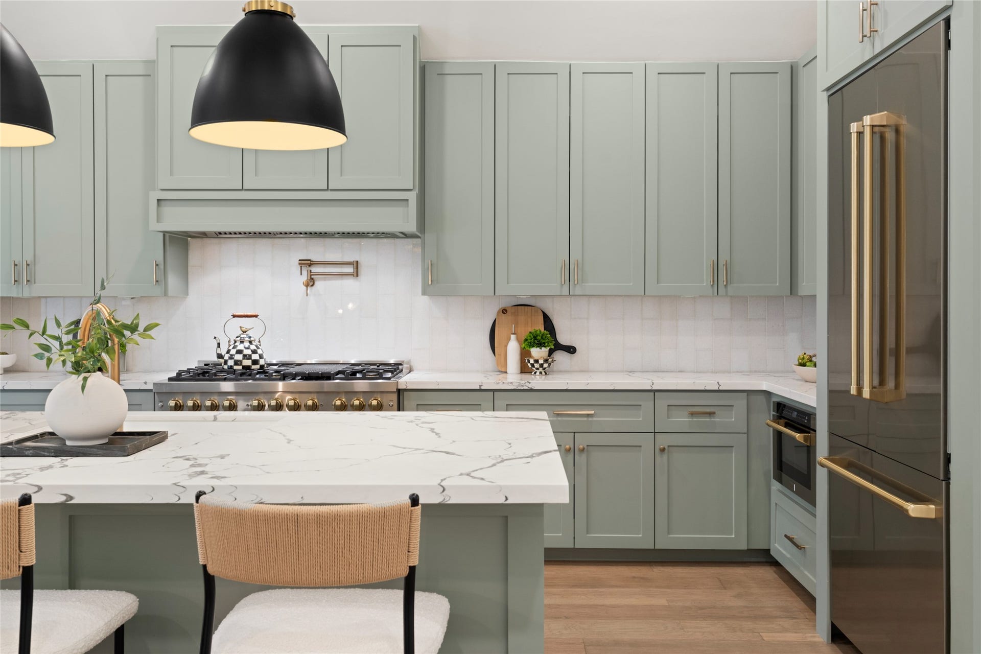 14 Lush Meadow Place, The Woodlands, TX 77381 The kitchen is an absolute showstopper, blending soft sage-green cabinetry with warm gold hardware and beautiful countertops.