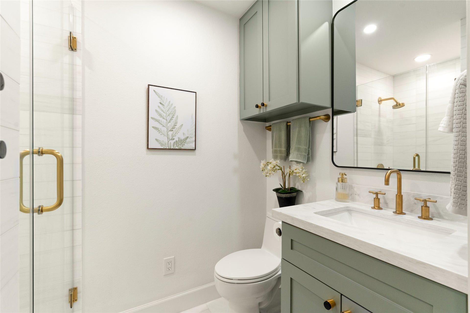 14 Lush Meadow Place, The Woodlands, TX 77381 Sage-green vanity, gold fixtures, and a beautifully tiled glass-enclosed shower.