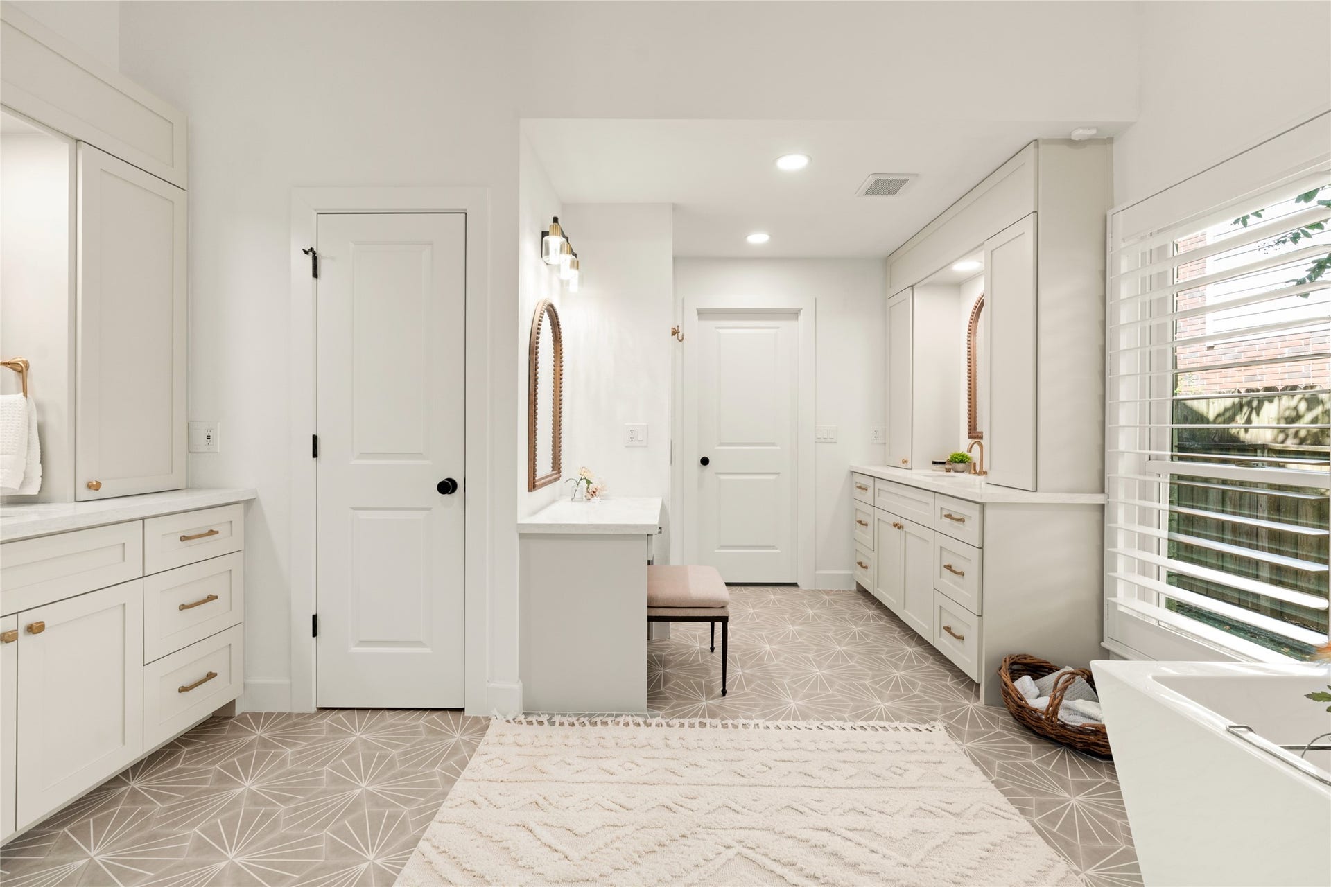 14 Lush Meadow Place, The Woodlands, TX 77381 Gorgeous geometric-patterned tile flooring sets the stage for a beautifully designed space featuring separate vanities, elegant gold fixtures, and a dedicated makeup station.
