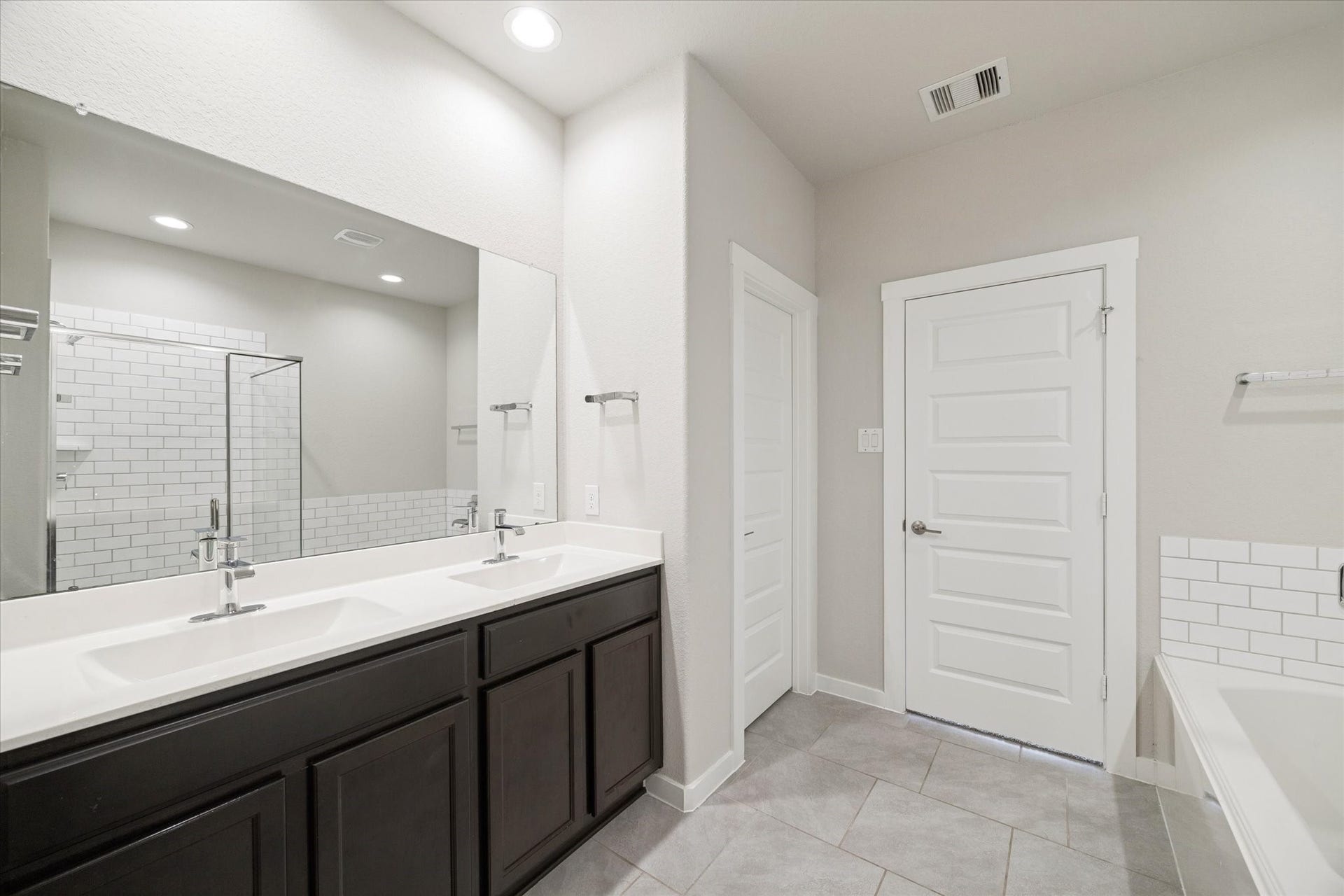 7503 Highland Chase Drive, Richmond, TX 77407 A well appointed primary bath featuring dual sinks with ample counter space and storage. Clean tile flooring, simple lines, and bright lighting create a functional environment designed for easy daily use.
