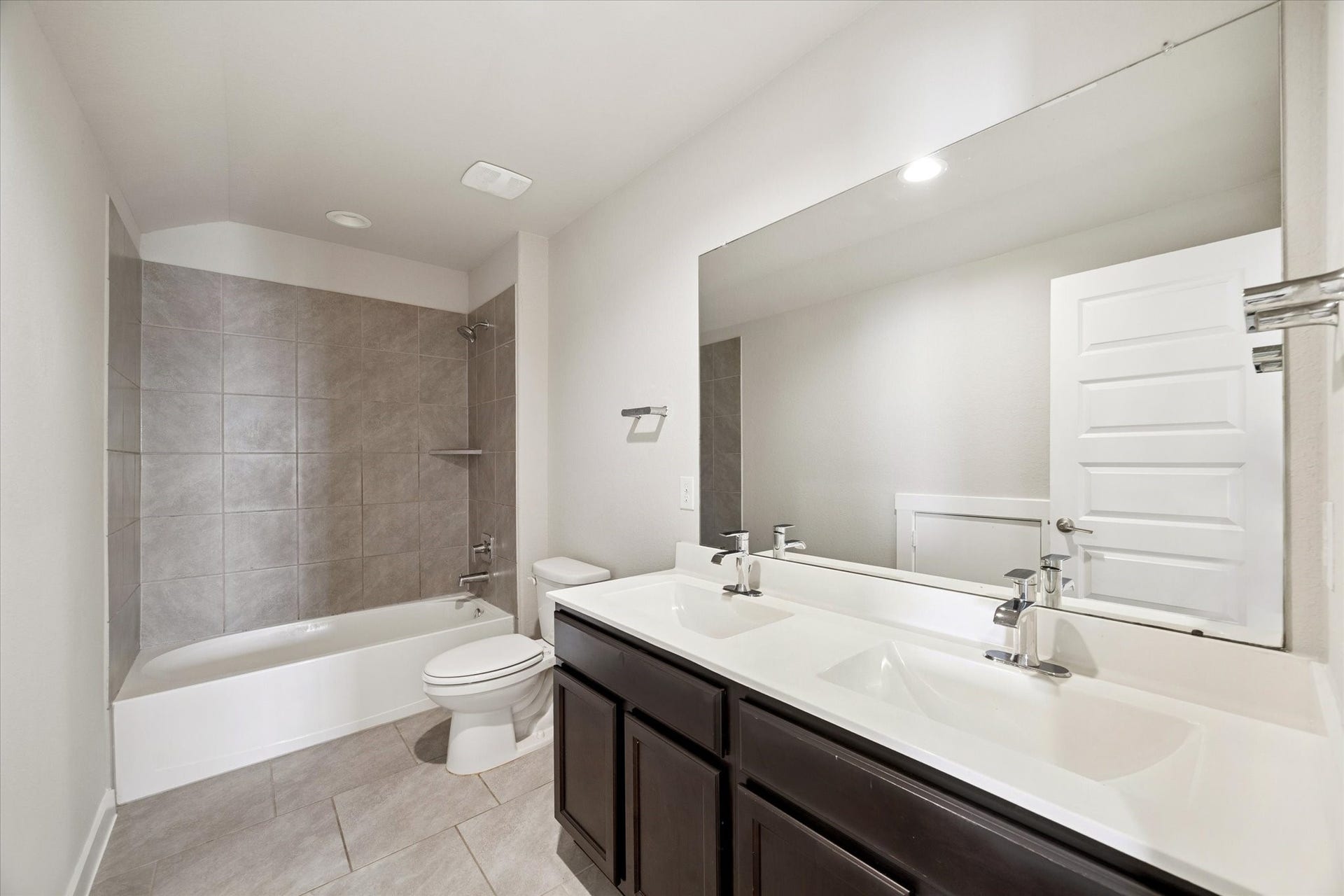7503 Highland Chase Drive, Richmond, TX 77407 This full bathroom blends practicality with a clean, modern aesthetic. A wide vanity with ample counter space, large mirror, and neutral tile surround the tub-shower combination, creating a bright, functional space well suited for guests or secondary bedrooms.