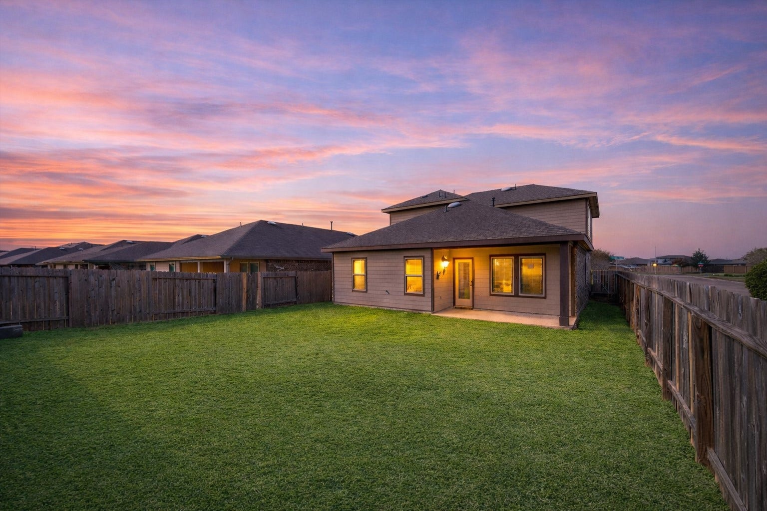 7503 Highland Chase Drive, Richmond, TX 77407 Wide, fully fenced backyard with plenty of green space to stretch out, play, or add a future pool. Covered patio glows at dusk, creating a relaxed setting for evening dinners or weekend gatherings.