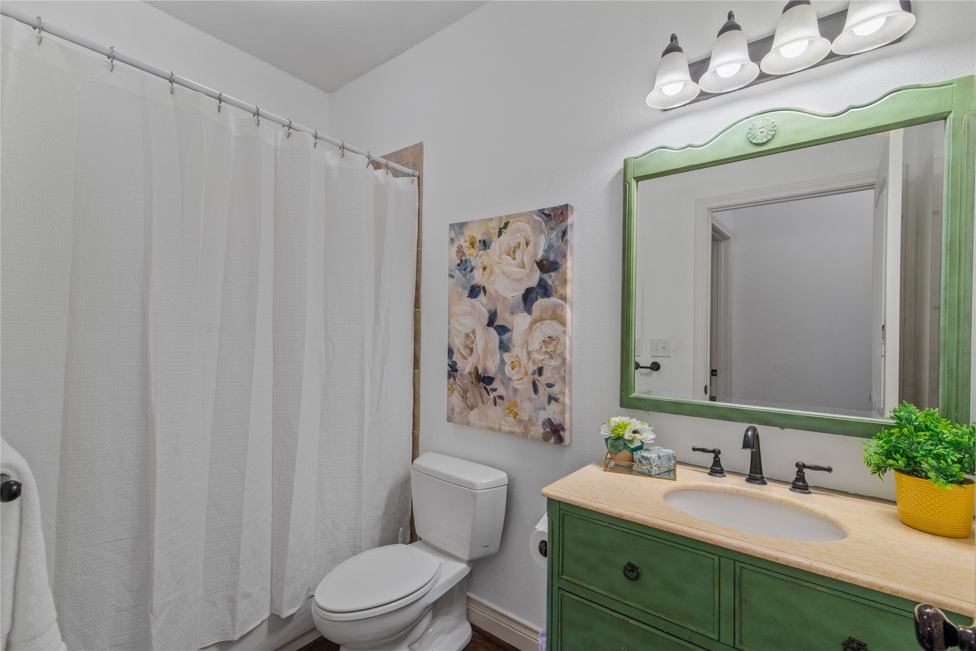 16144 Firetower Road, Conroe, TX 77306 Privately tucked away near the flex room and additional bedrooms, this full bathroom features a tub/shower combination and a charming green vanity with coordinating mirror.