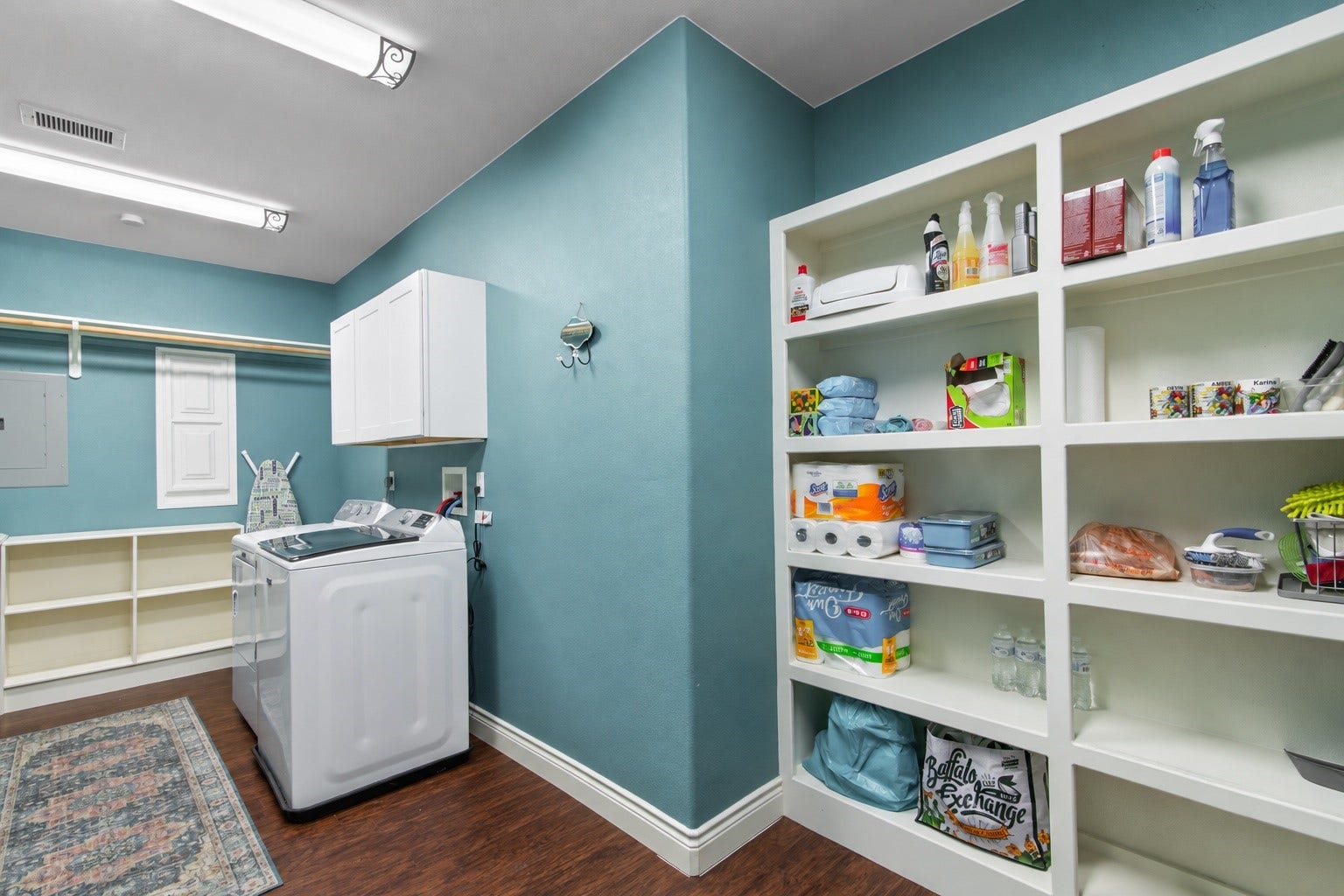 16144 Firetower Road, Conroe, TX 77306 Large laundry room featuring extensive built-in shelving, overhead cabinetry, and a hanging rod for convenient clothing care and household storage.