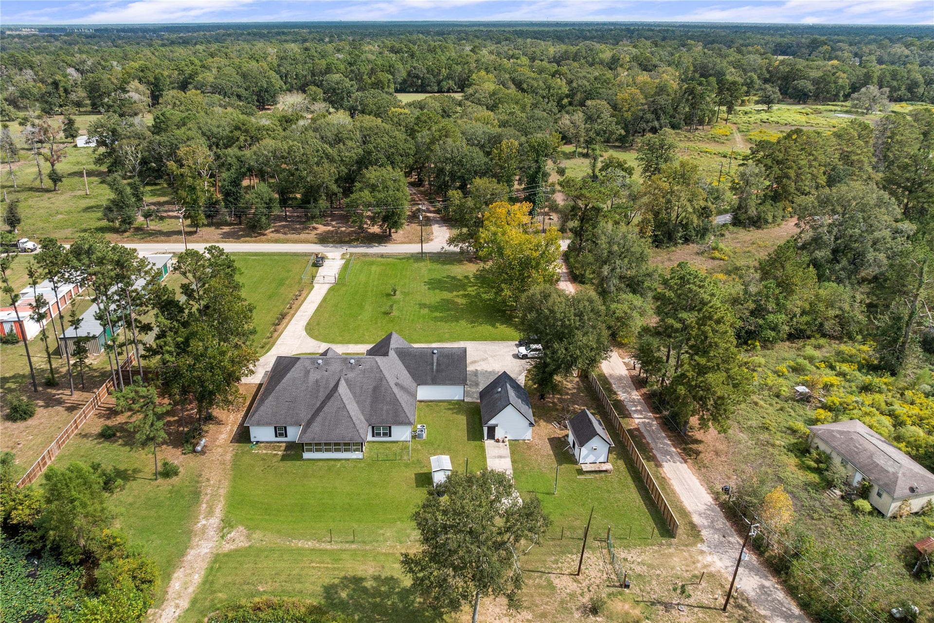 16144 Firetower Road, Conroe, TX 77306 Aerial view showcases the homes placement on 1.77 acres, with an extended driveway, detached garage, workshop, water well house, and generous outdoor space.