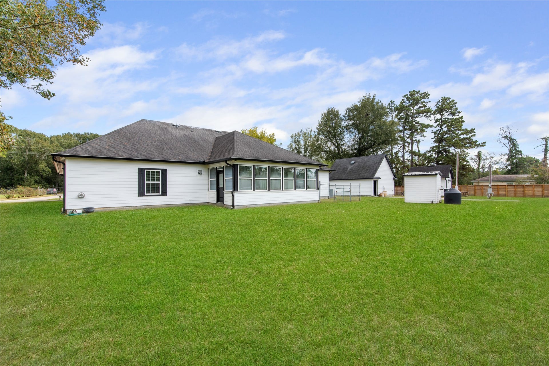 16144 Firetower Road, Conroe, TX 77306 Expansive backyard with a view of the propertys private water well, workshop, and detached garage, offering versatile space for projects, storage, and outdoor enjoyment.