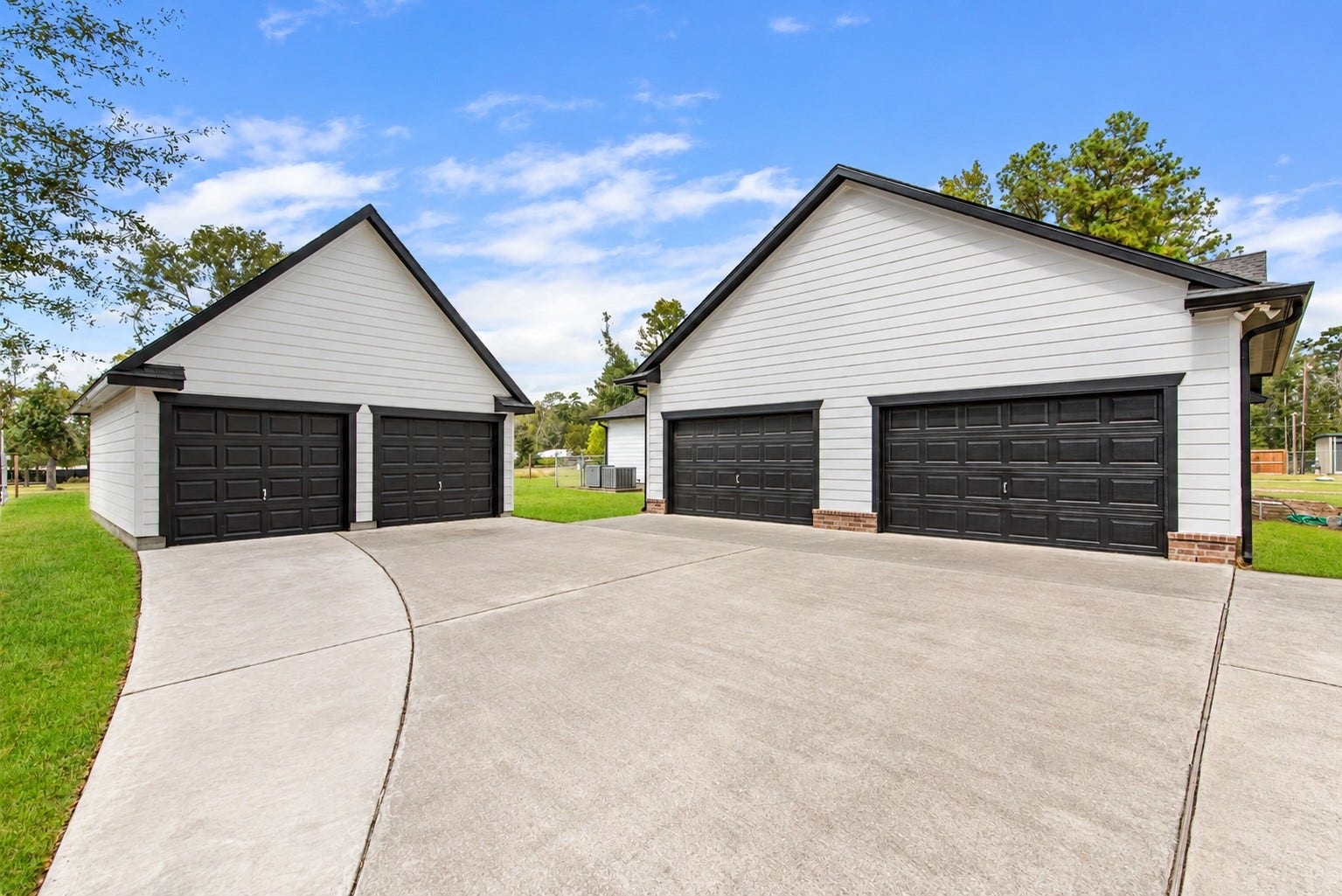 16144 Firetower Road, Conroe, TX 77306 An oversized attached two-car garage and a detached two-car garage provide four total garage spaces, with an expansive concrete driveway for additional parking and easy maneuvering.