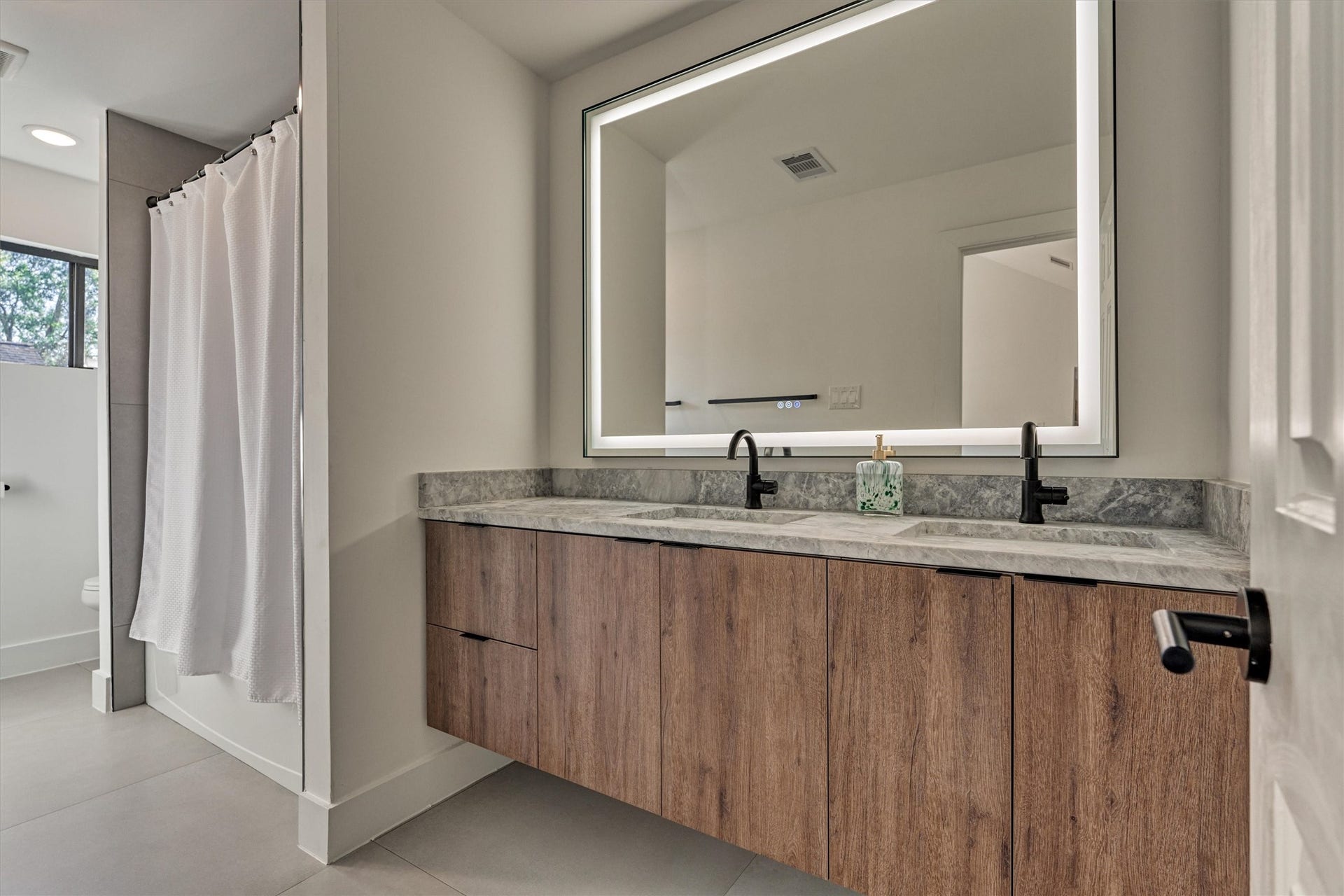 402 Susan Lane, Conroe, TX 77385 Spacious full bath with lighted mirror, floating dual sink vanity, and tub/shower combo flawlessly serves the upstairs.