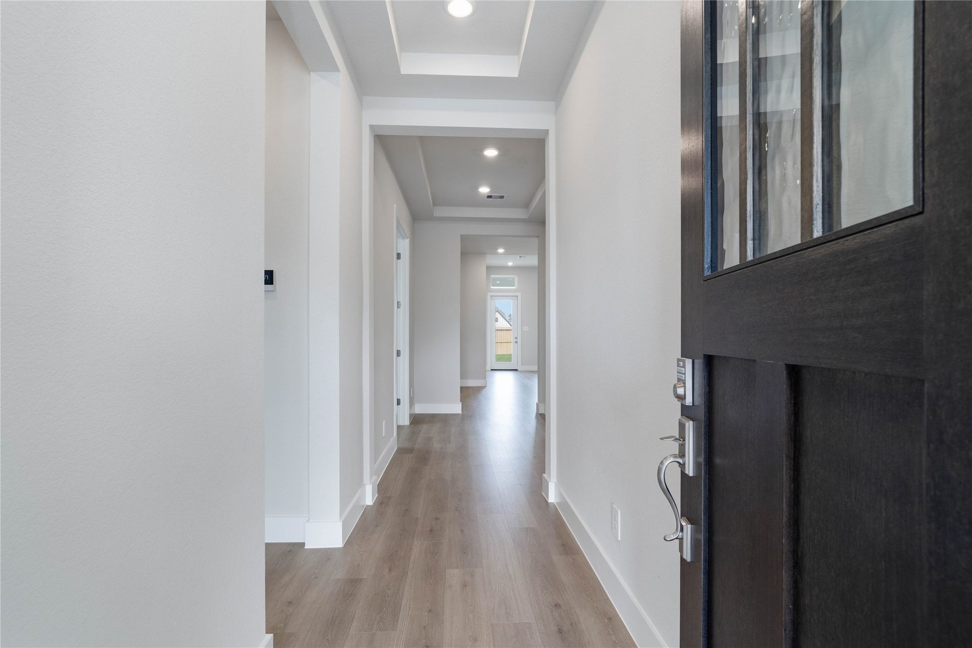 Welcome inside to a bright and inviting entryway that sets the tone for this modern home. Crisp neutral toned walls and abundant natural light create an open and spacious feel throughout the hallway. The laminate flooring extends seamlessly through the area, offering both aesthetic appeal and durability.