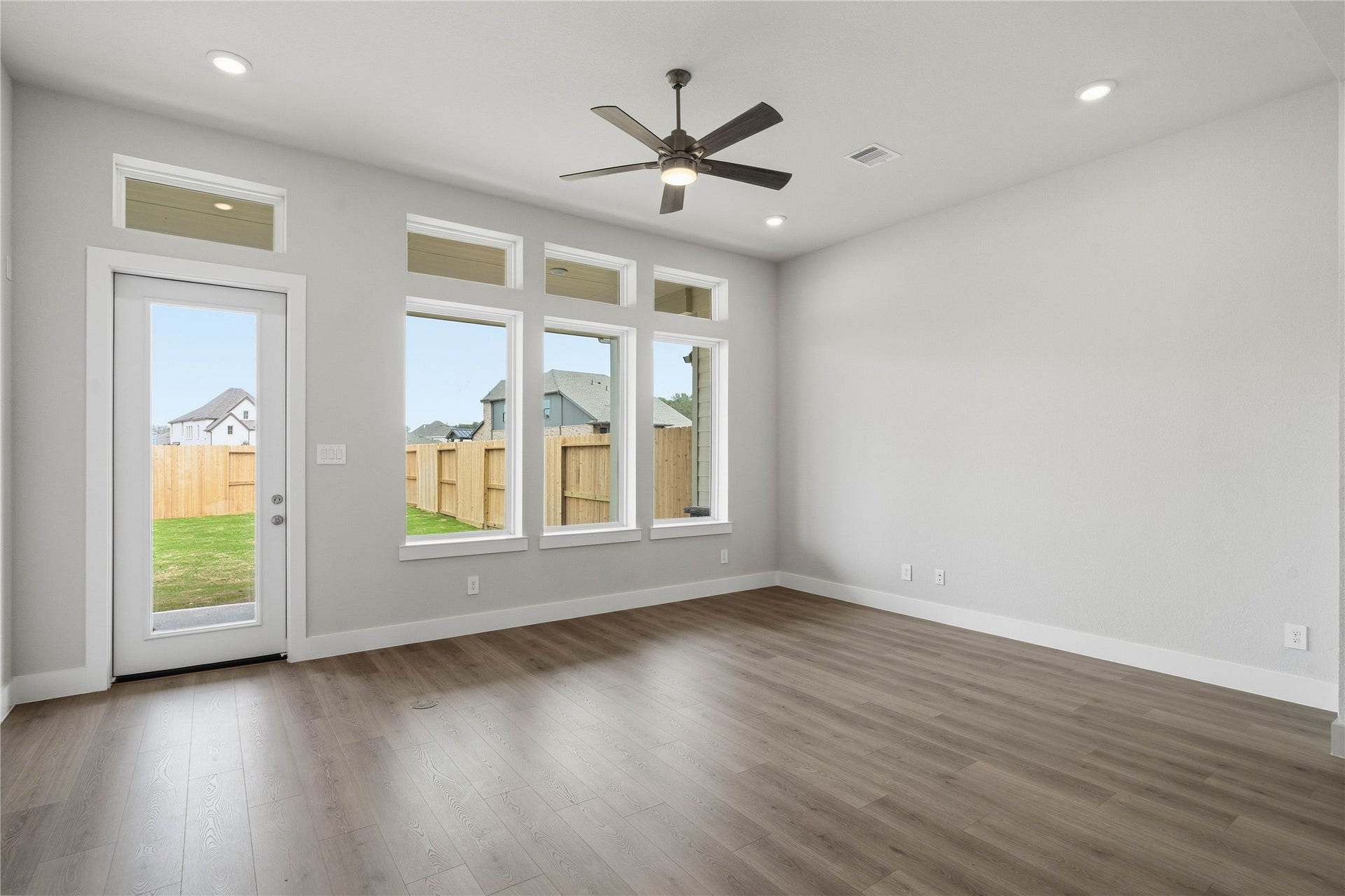 Soaring, tall windows frame the living space, bathing the room in natural light and highlighting the architectural volume of the space. A convenient back door provides direct and easy access to a comfortable covered patio, effortlessly extending your living space outdoors for year-round enjoyment and entertaining.