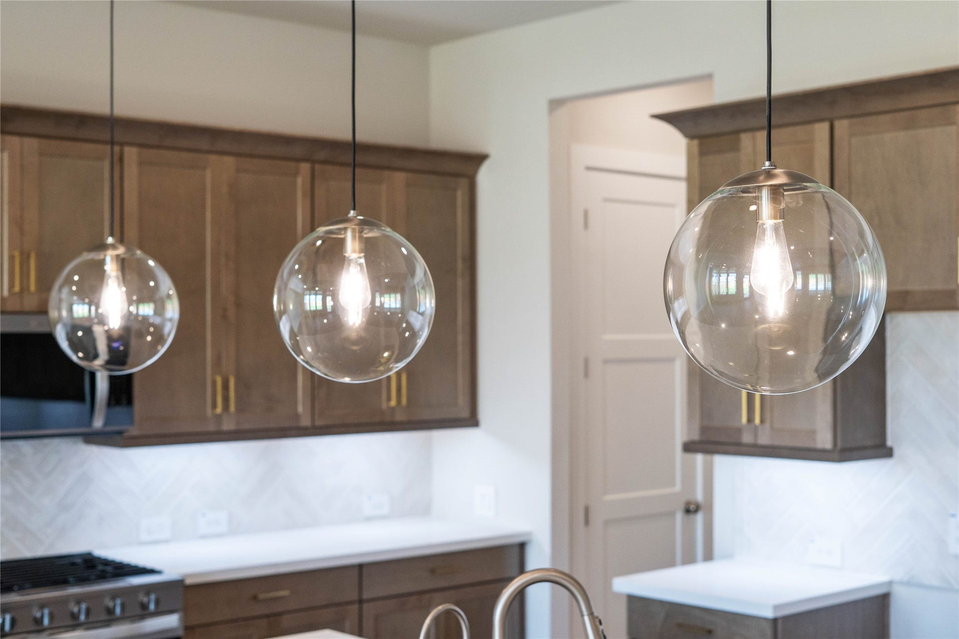 Atwell pendant lights hang above the island, adding a touch of modern design, complemented by recessed lighting throughout the ceiling for overall illumination.
