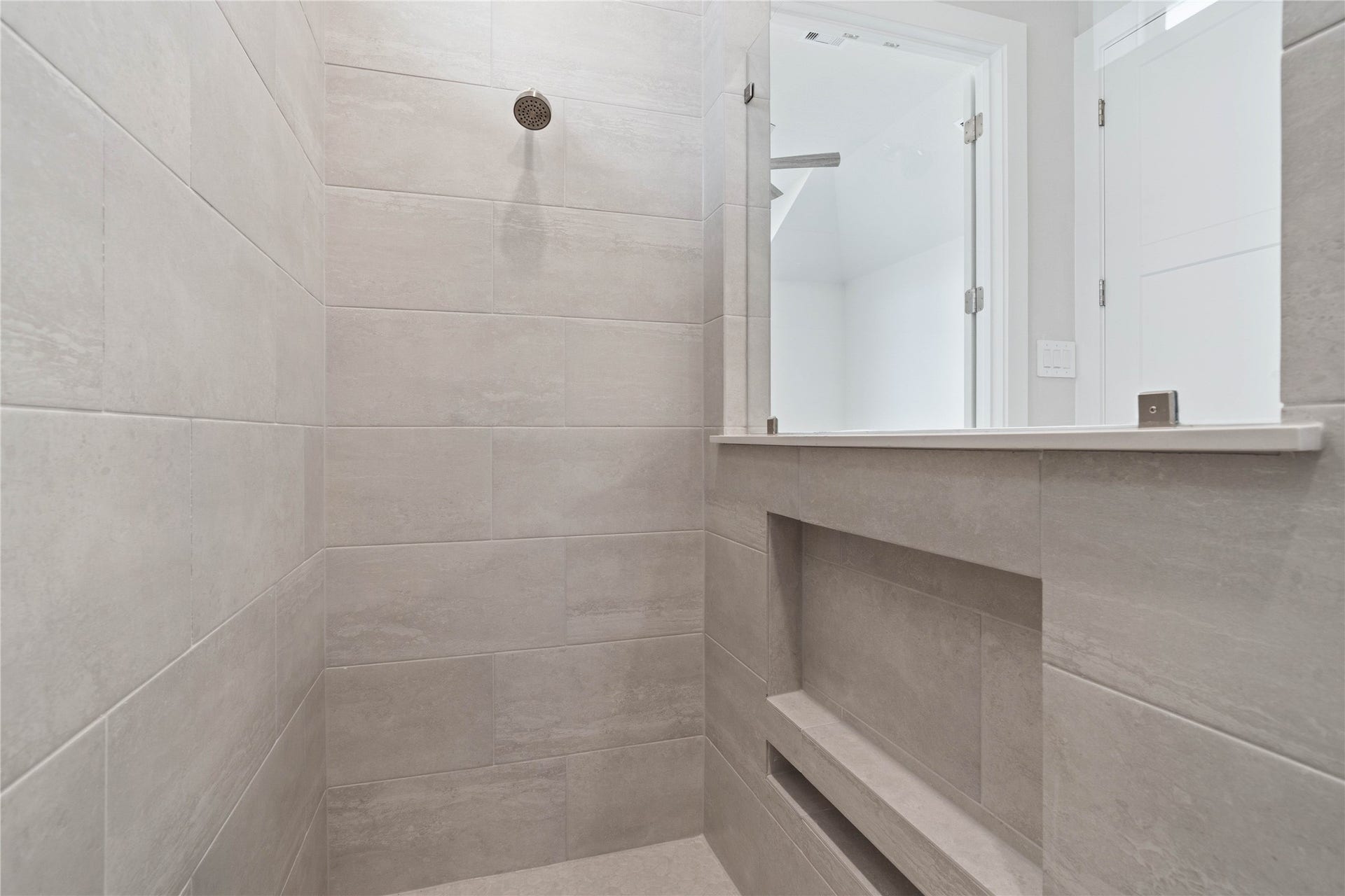 Indulge in the spa-like luxury of this primary bathroom, featuring a stunning walk-in shower adorned with tile surround and a sleek showerhead.