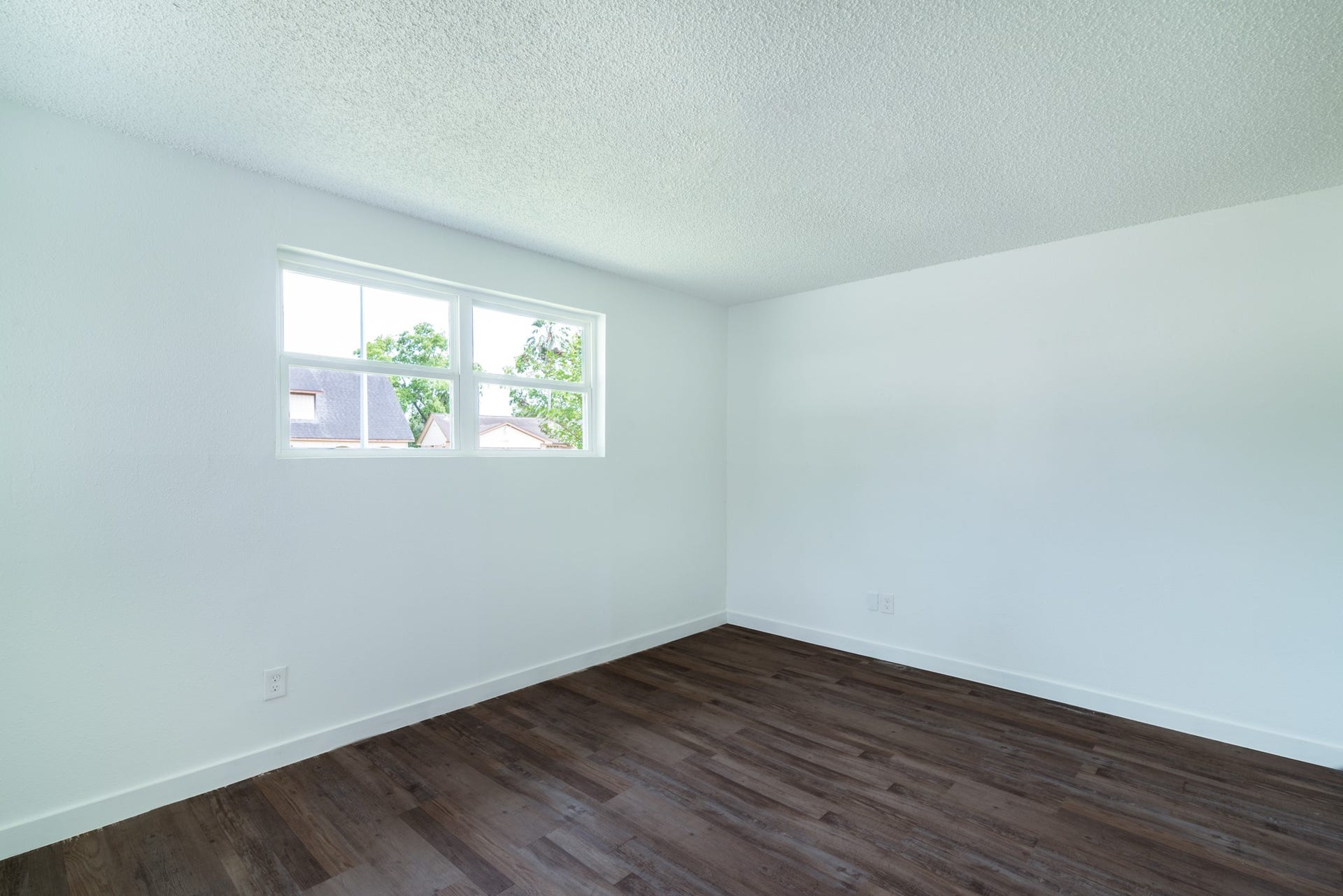 15910 Plagens Lane, Missouri City, TX 77489 Bright room with fresh white walls, a large window for natural light, and sleek dark wood flooring.