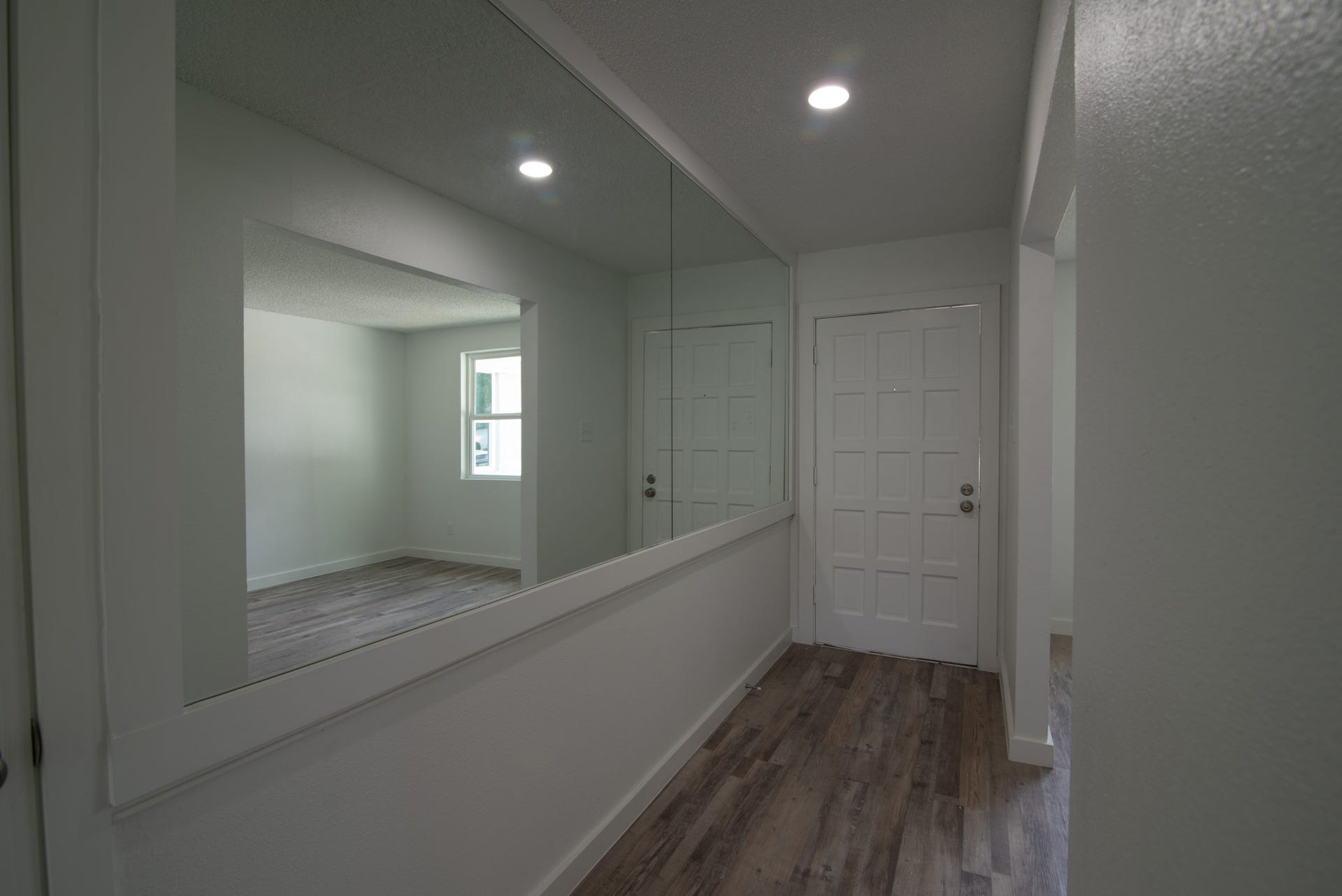 15910 Plagens Lane, Missouri City, TX 77489 Bright entryway with sleek wood flooring, a large wall mirror, and recessed lighting, offering a welcoming first impression.