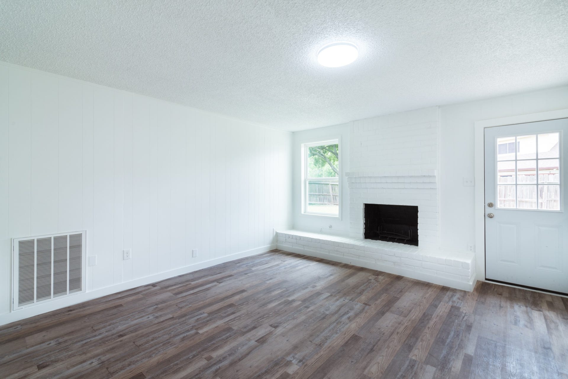15910 Plagens Lane, Missouri City, TX 77489 Bright and inviting living room featuring a cozy fireplace, beautiful wood flooring, and ample natural light from large windows.
