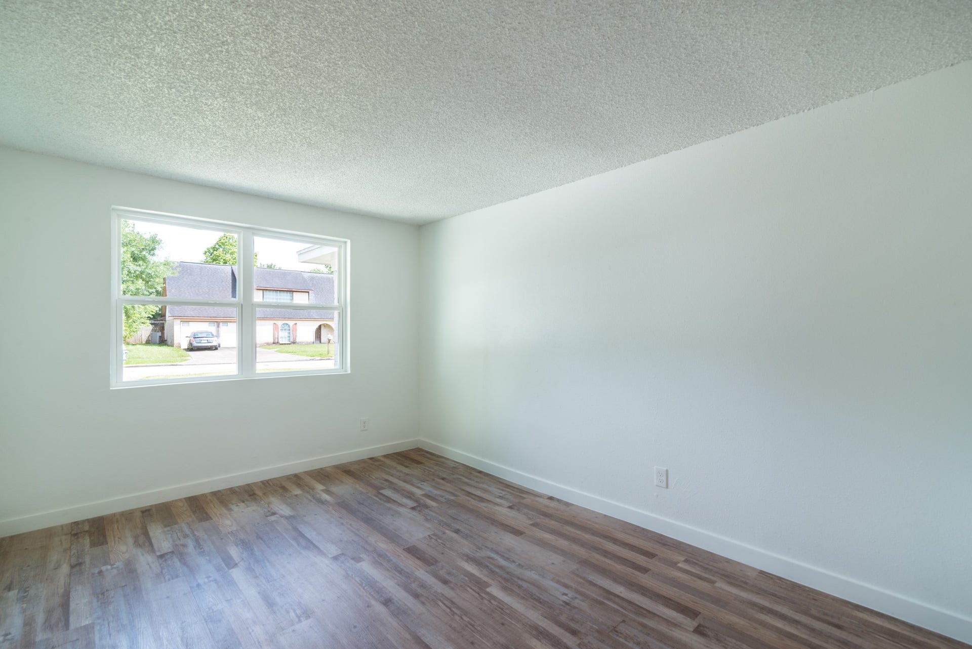 15910 Plagens Lane, Missouri City, TX 77489 Bright and inviting room with large windows, fresh white walls, and stylish wood-look flooring, perfect for a cozy living space or office.