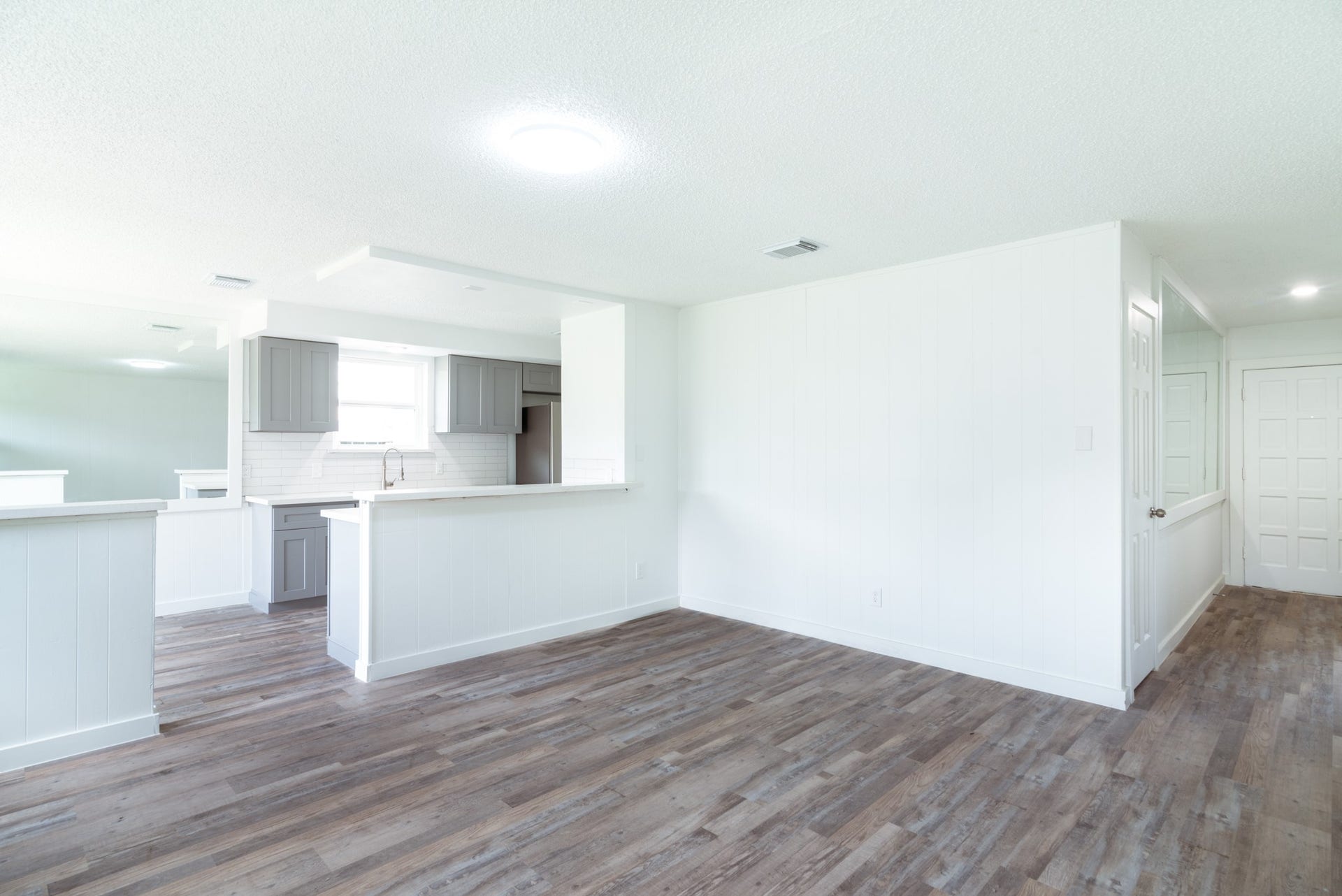 15910 Plagens Lane, Missouri City, TX 77489 Bright and spacious open-concept living area with sleek wood flooring and a modern kitchen featuring stylish gray cabinetry and a breakfast bar.
