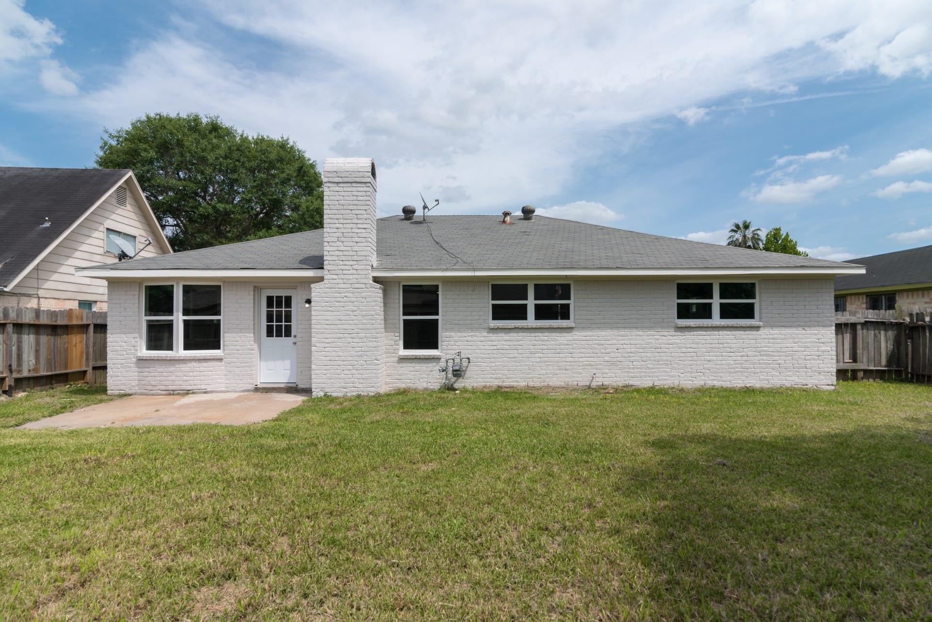 15910 Plagens Lane, Missouri City, TX 77489 Charming single-story home with a spacious backyard, featuring a white brick exterior and ample windows for natural light.