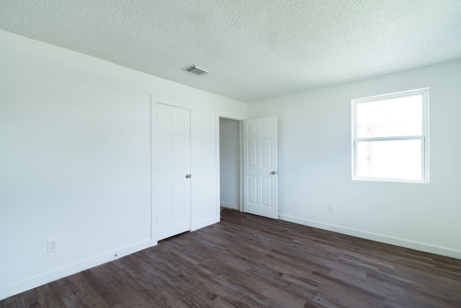 15910 Plagens Lane, Missouri City, TX 77489 Bright, airy bedroom featuring fresh white walls, rich hardwood flooring, and abundant natural light streaming through a large window.