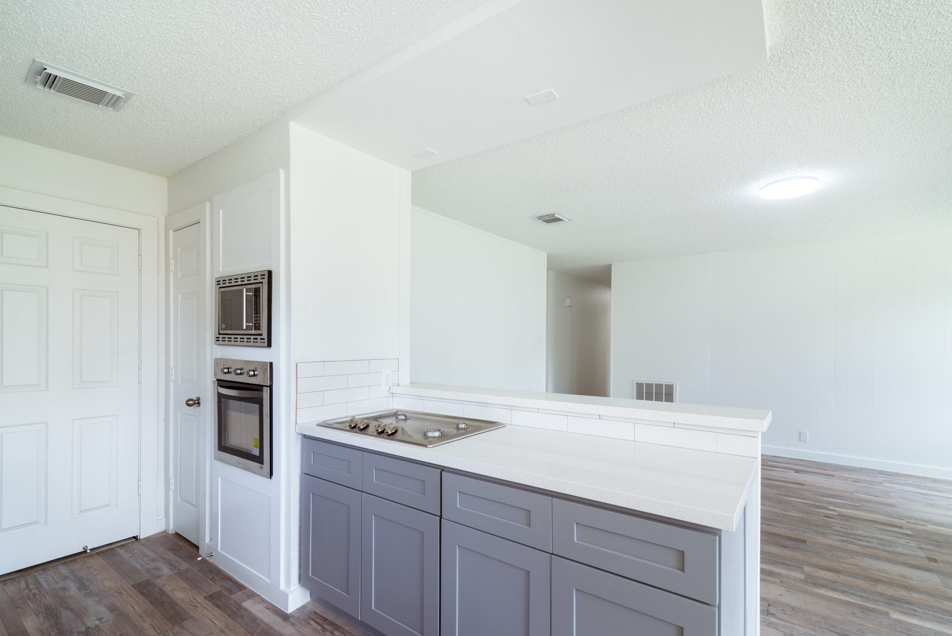 15910 Plagens Lane, Missouri City, TX 77489 Modern kitchen area featuring sleek gray cabinetry, integrated appliances, and a clean, open layout with stylish wood flooring.