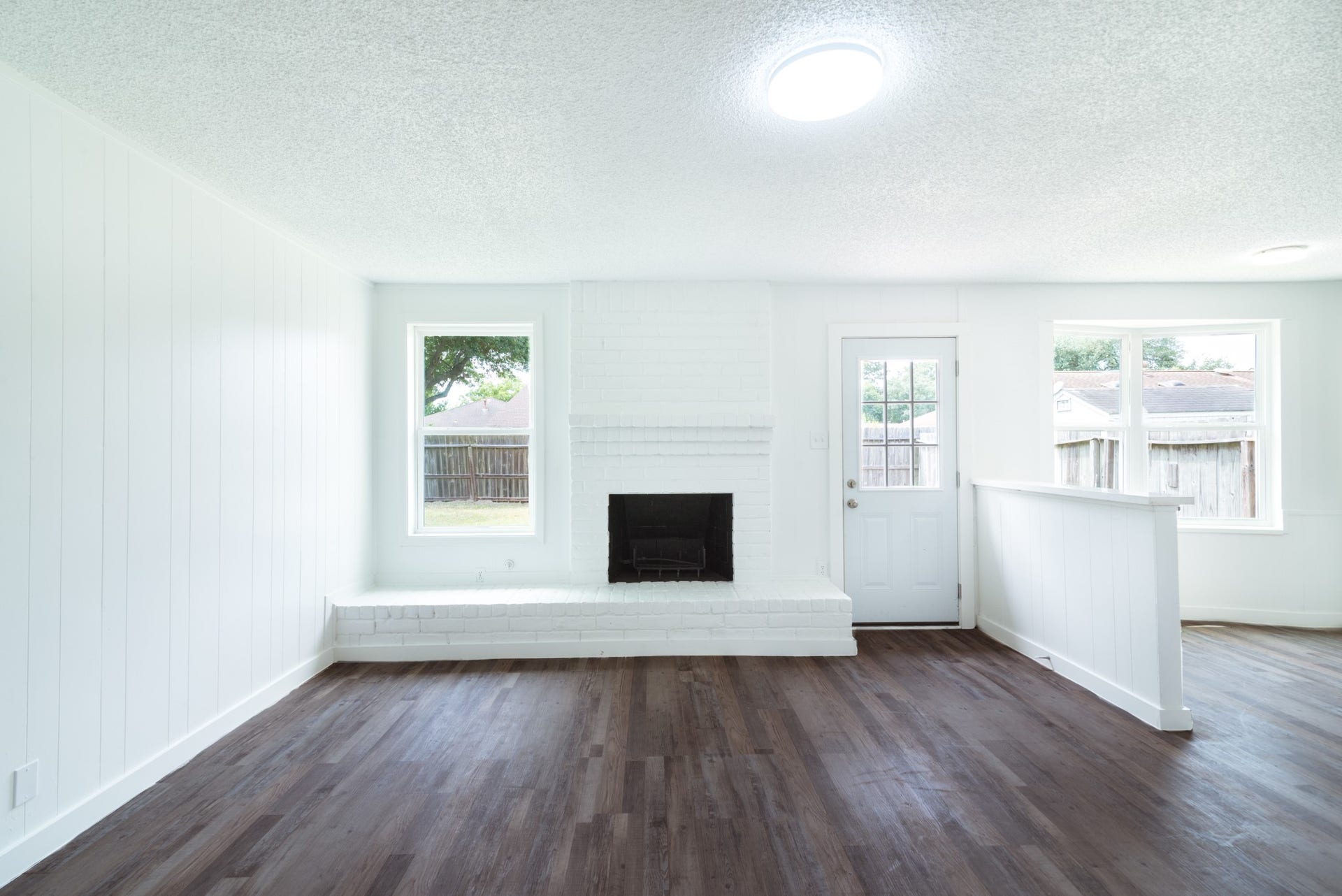 15910 Plagens Lane, Missouri City, TX 77489 Bright and inviting living room with a cozy white brick fireplace, rich wood flooring, and ample natural light from large windows and a glass-paneled door.
