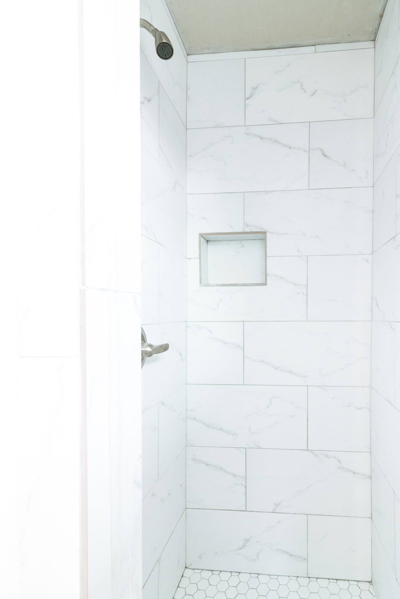 15910 Plagens Lane, Missouri City, TX 77489 Elegant shower featuring sleek white marble tiles and a convenient built-in shelf for storage.