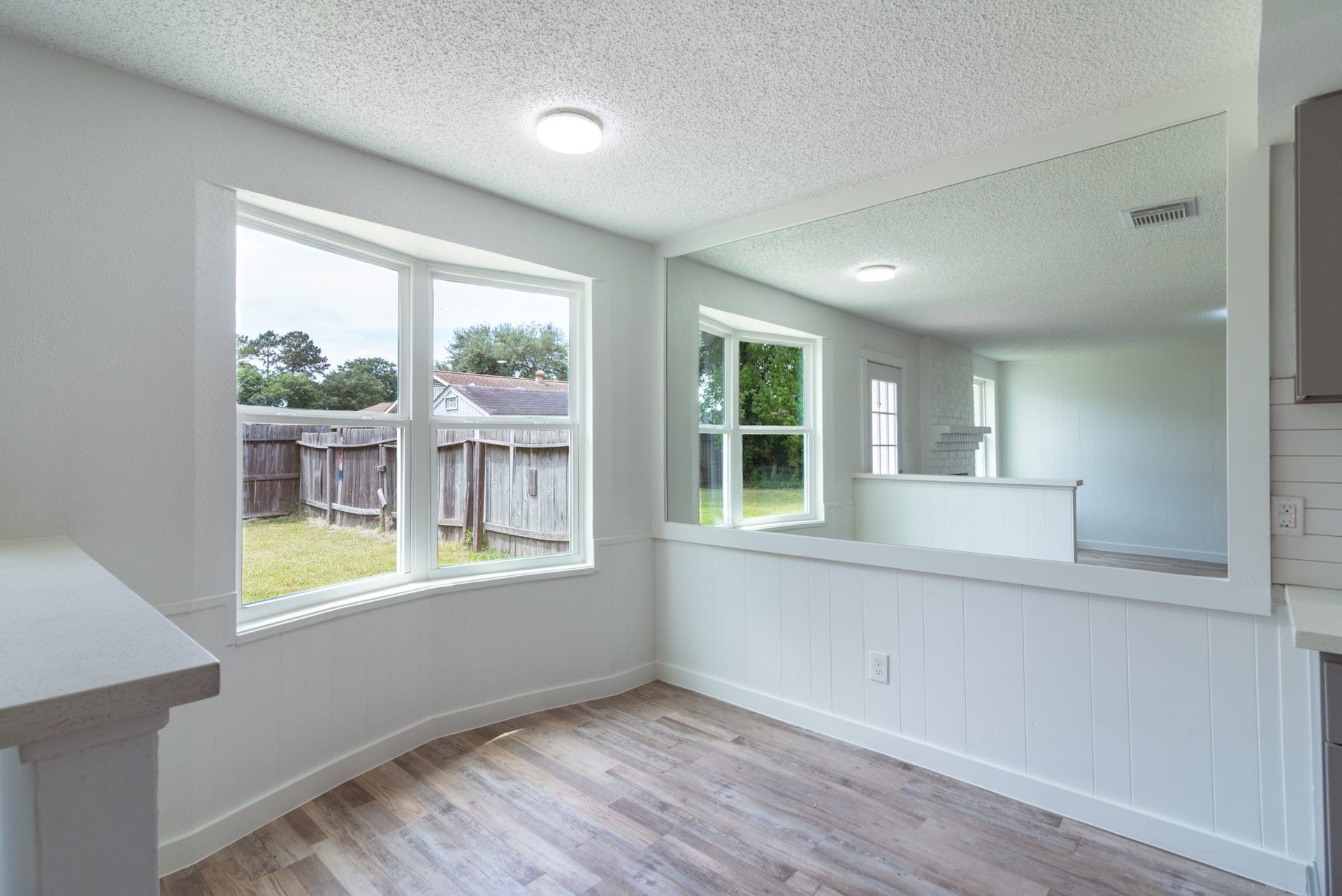 15910 Plagens Lane, Missouri City, TX 77489 Bright and inviting living space featuring large windows with views of the backyard, complemented by stylish wood flooring and crisp white walls.