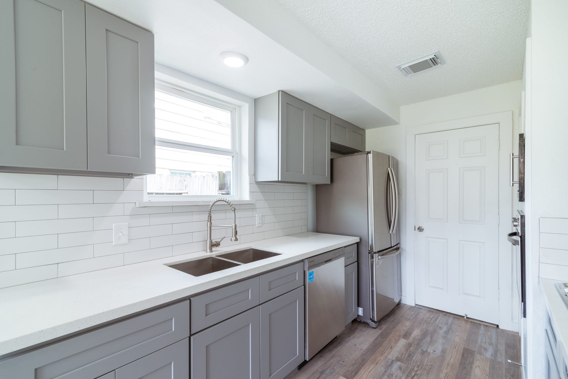 15910 Plagens Lane, Missouri City, TX 77489 Modern kitchen with sleek gray cabinetry, stainless steel appliances, and a stylish subway tile backsplash.