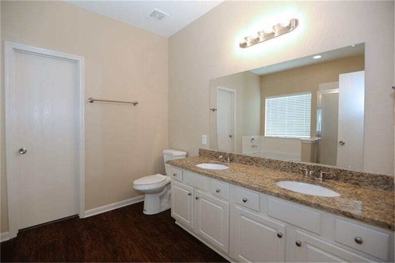 3126 Richland Spring Lane, Sugar Land, TX 77479 Spacious bathroom featuring a double vanity with granite countertops, ample cabinetry, and a large mirror, complemented by elegant lighting and a sleek tile floor.