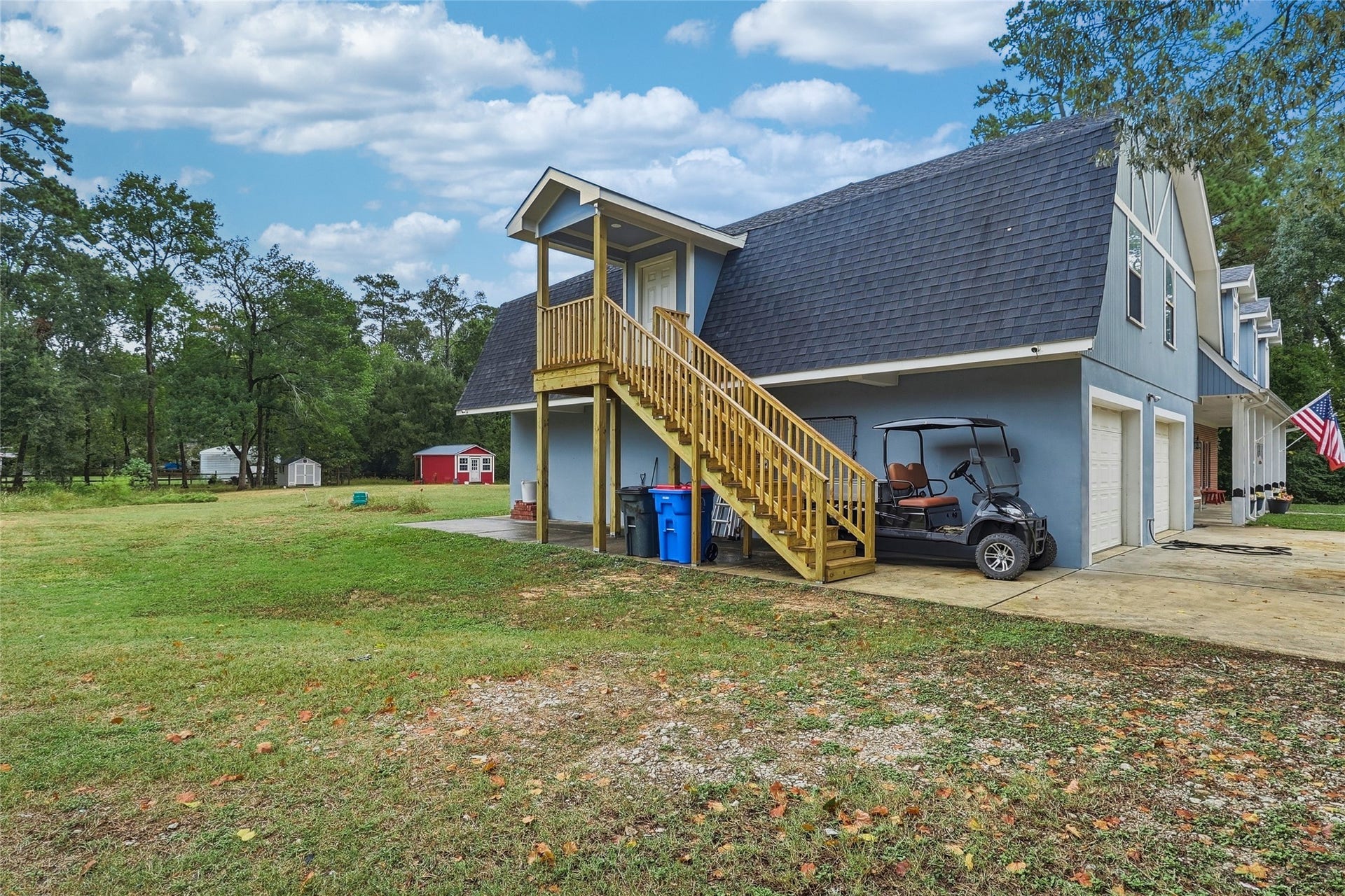 8714 Holly Hills Drive, Tomball, TX 77375 Exterior view showcasing the garage apartment entrance, set against the spacious, tree-lined side yard on two acres.