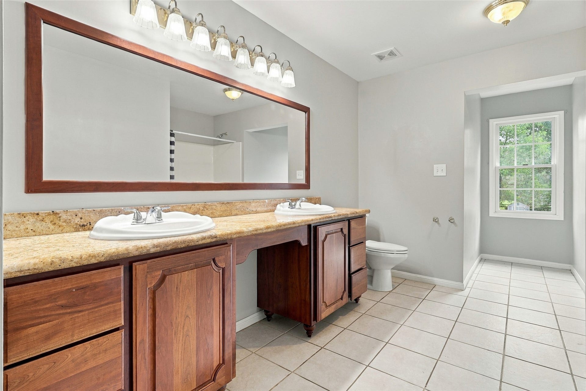 8714 Holly Hills Drive, Tomball, TX 77375 Generously sized main bath highlighted by dual sinks, vanity area, sleek updated lighting, and a newly updated mirror.