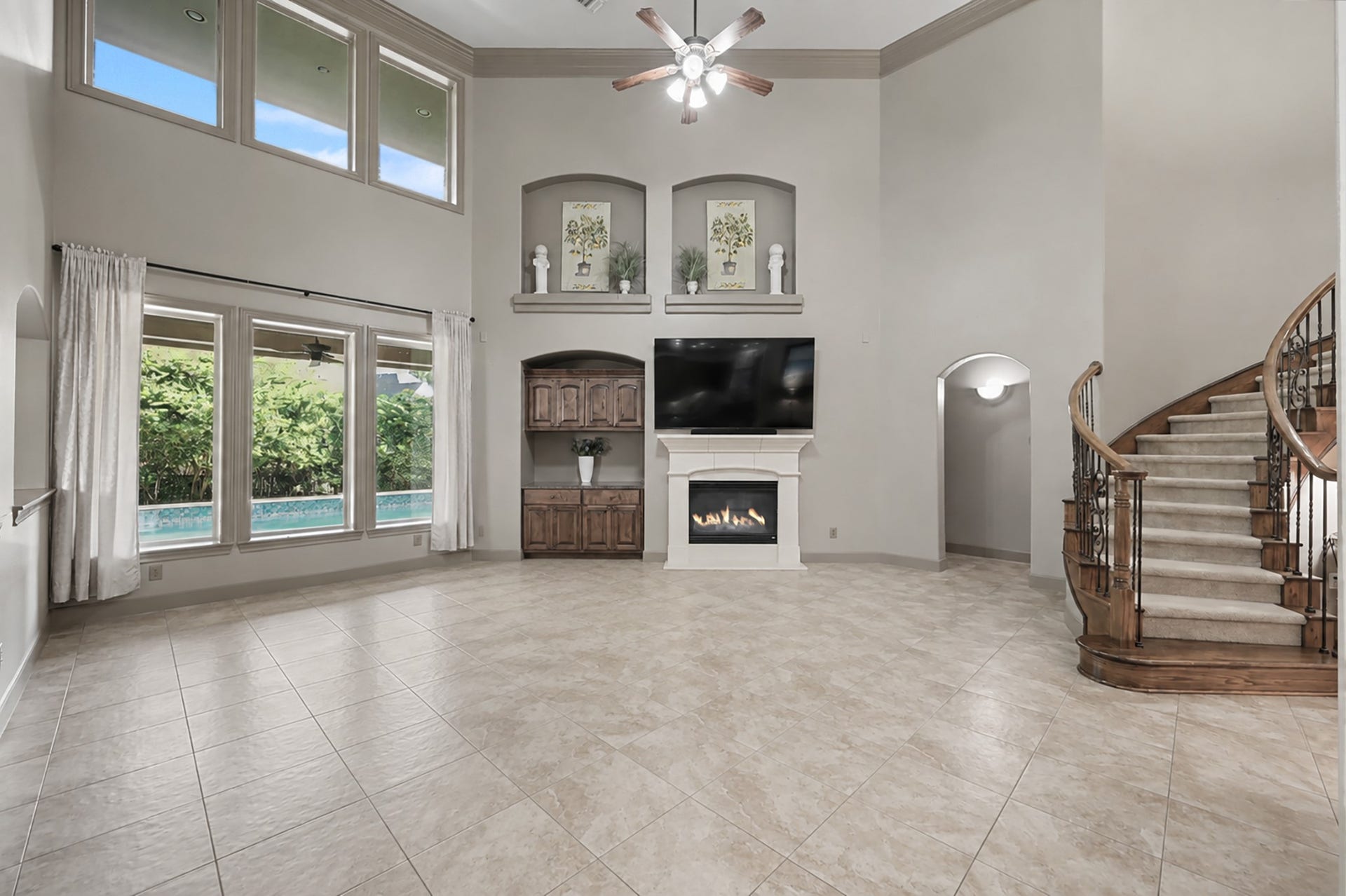 An unfurnished perspective highlighting the true size and architectural depth of the main living spacefeaturing high ceilings, sweeping staircase curves, and wall-to-wall natural light.