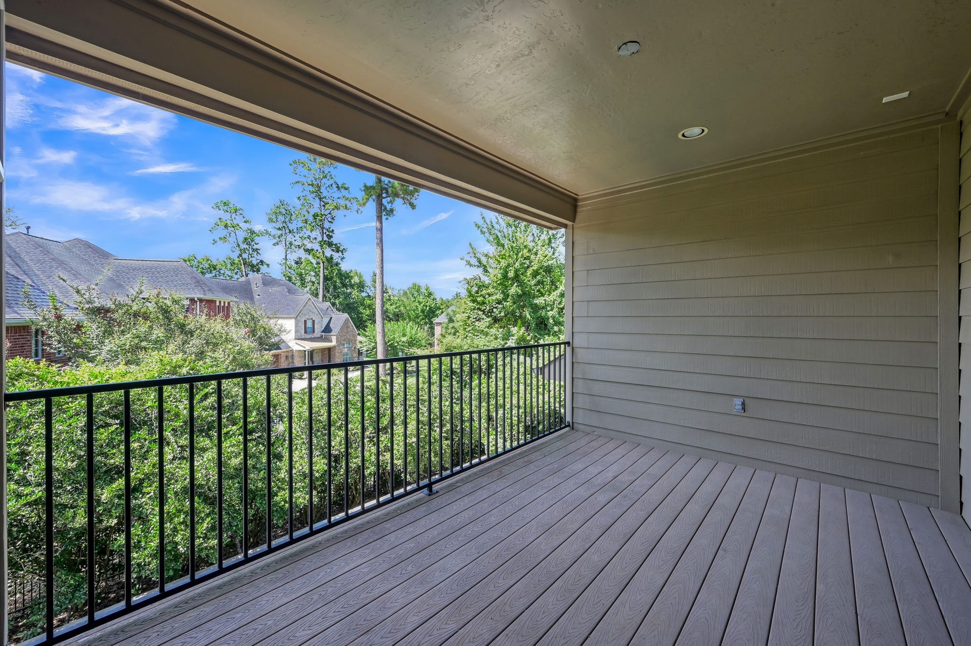 This home features a spacious covered balcony with a wood-look deck and railing. Perfect for relaxation and enjoying the outdoors.
