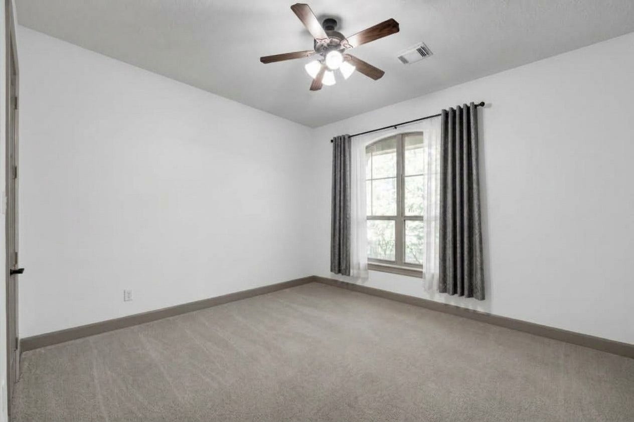 Second Downstairs Guest Suite

Main-floor guest bedroom featuring an ensuite bath for total privacy. Highlights include a slate-blue accent wall, neutral carpeting, a central ceiling fan, and a large arched window that fills the space with bright natural light.