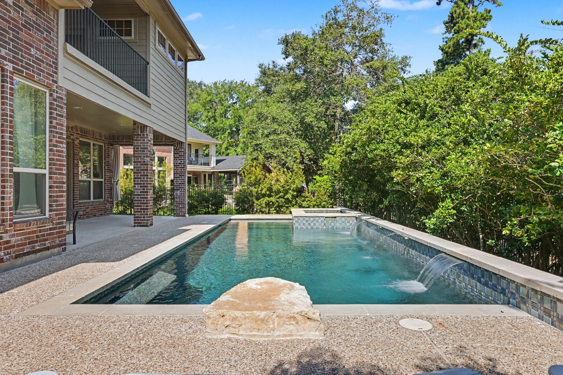 Resort-style pool featuring water shear falls, elevated spa, and ample decking.