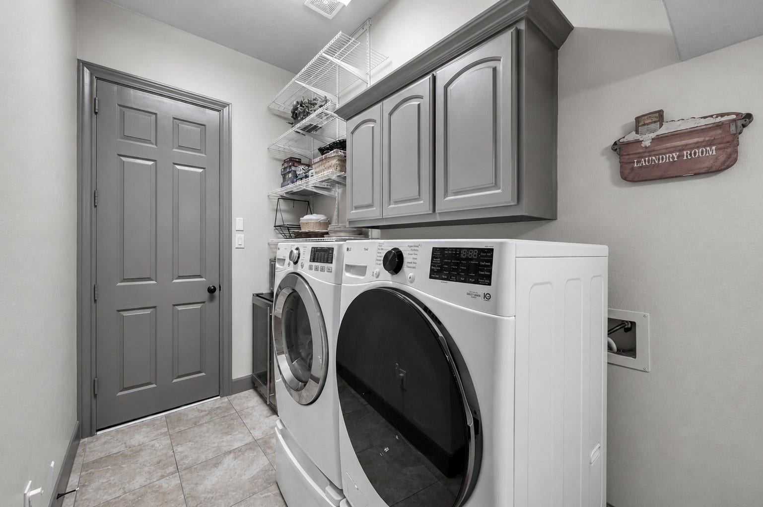 Utility room with ample space for the washer and dryer, plus cabinetry, a sink area, and additional storage.