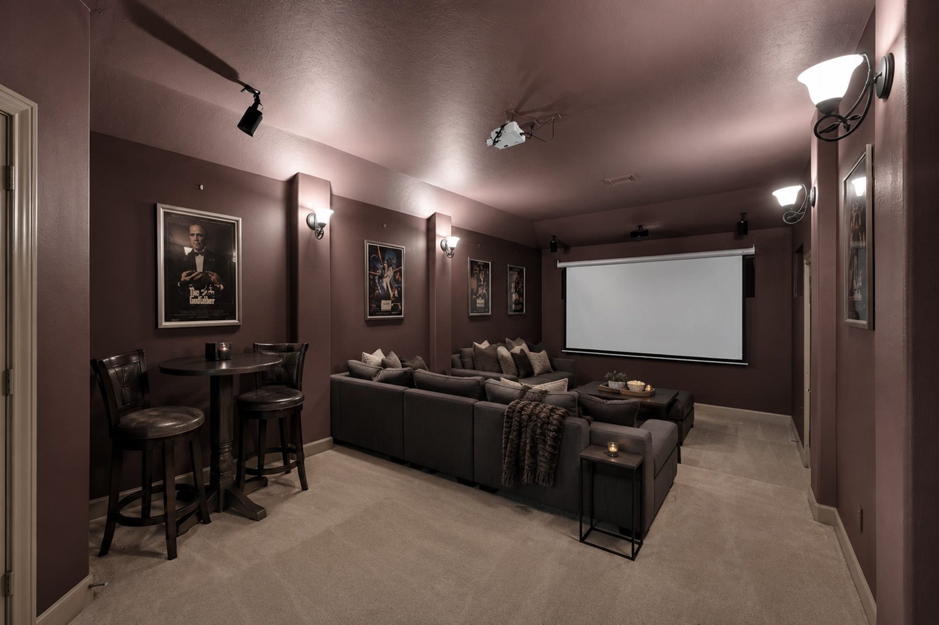 Home theater with a projector screen, built-in wall lights, and a cozy, carpeted floor, perfect for movie nights. (Virtually Staged)
