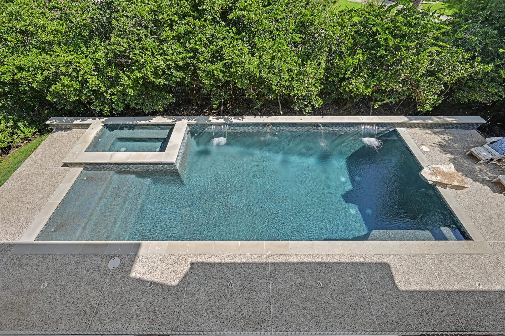 Balcony view overlooking the backyard oasis, featuring an 8-ft deep heated pool, attached spa, and surrounding deck, all framed by mature trees for added privacy