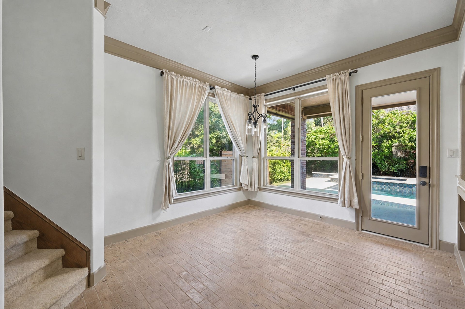 Bright breakfast room with brick flooring, large windows, and access to the backyard/patio area.