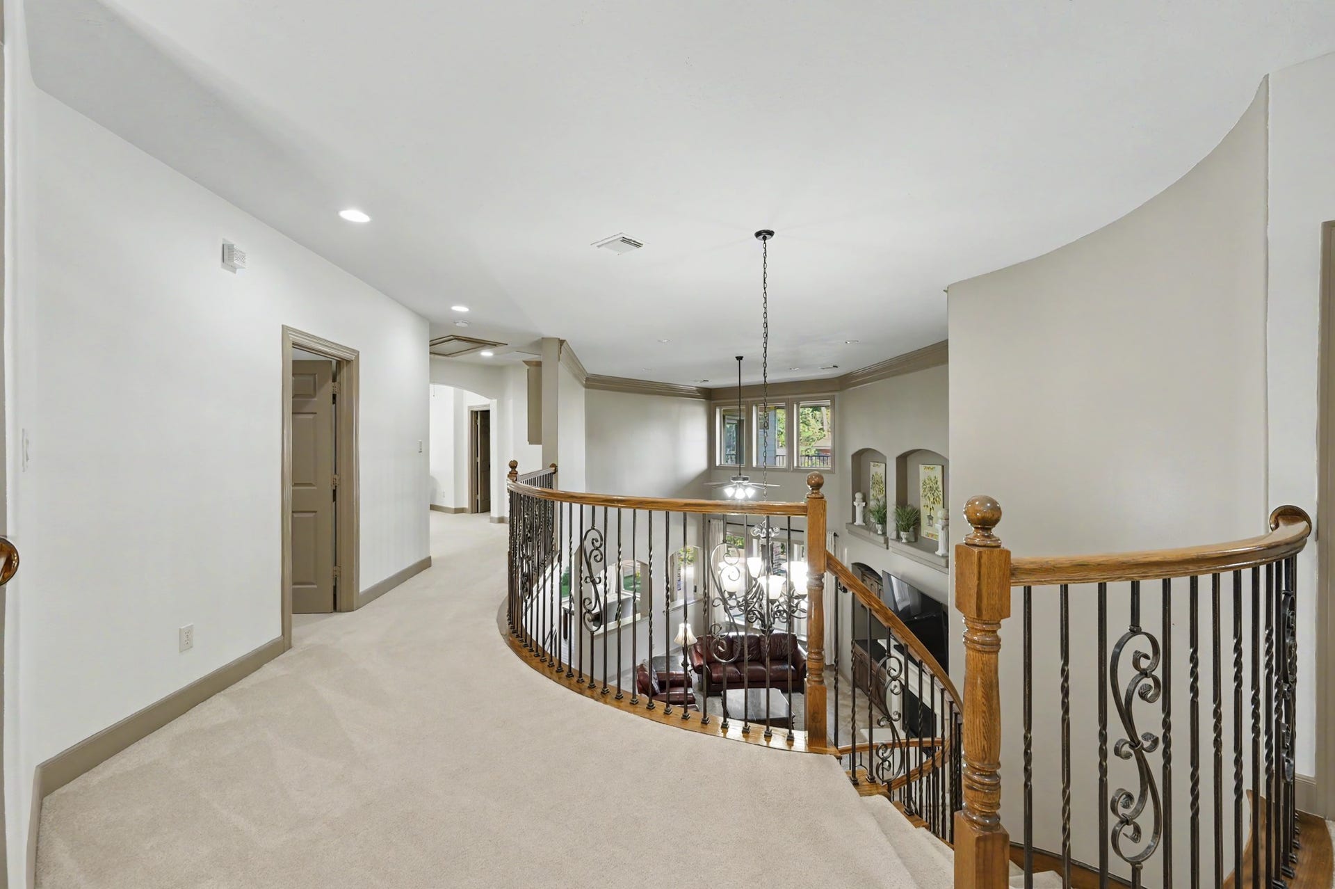 Upstairs landing with curved railing, open view to the foyer/family room, and access to bedrooms.