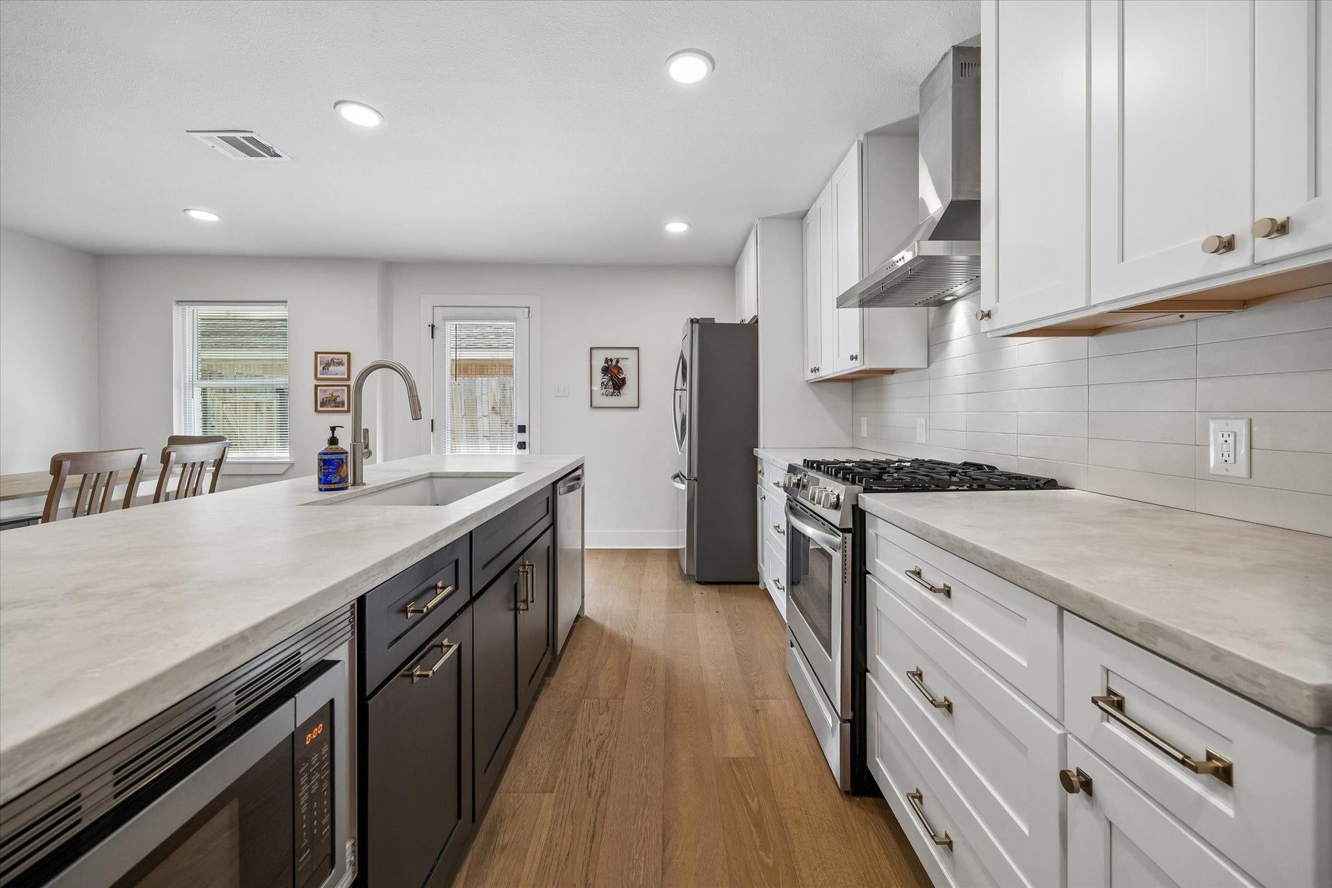 2018 Libbey Drive, Houston, TX 77018 Crisp white cabinetry is balanced by a contrasting island, warm wood flooring and brushed gold hardware. Stainless appliances, a gas range and streamlined vent hood complete the polished kitchen.