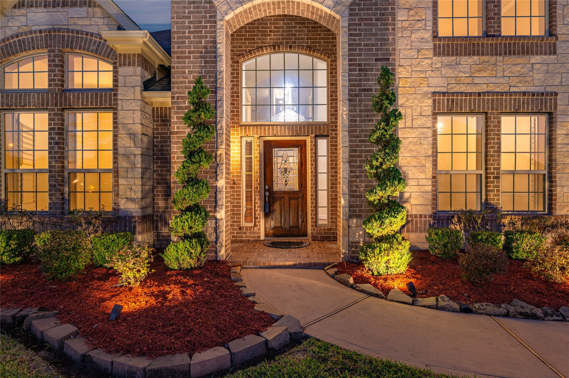 2322 Ashley Falls Lane, League City, TX 77573 Detailed view of elevation B with professionally maintained lawn, extensive landscaping lighting, exterior stone accent and 2-story covered front porch.