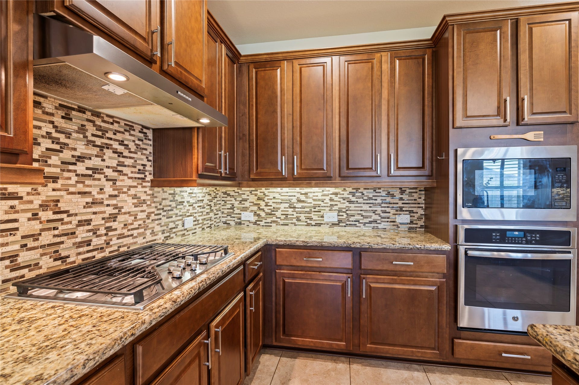2322 Ashley Falls Lane, League City, TX 77573 Attractive backsplash compliments the 5-burner gas range; built-in oven and microwave surrounded by maple kitchen cabinetry.