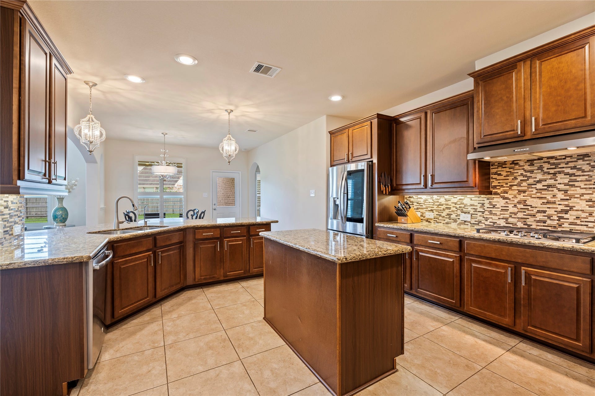 2322 Ashley Falls Lane, League City, TX 77573 Spacious island kitchen with custom pendent lighting over the breakfast bar, hardware on the cabinets and stainless steel appliances.