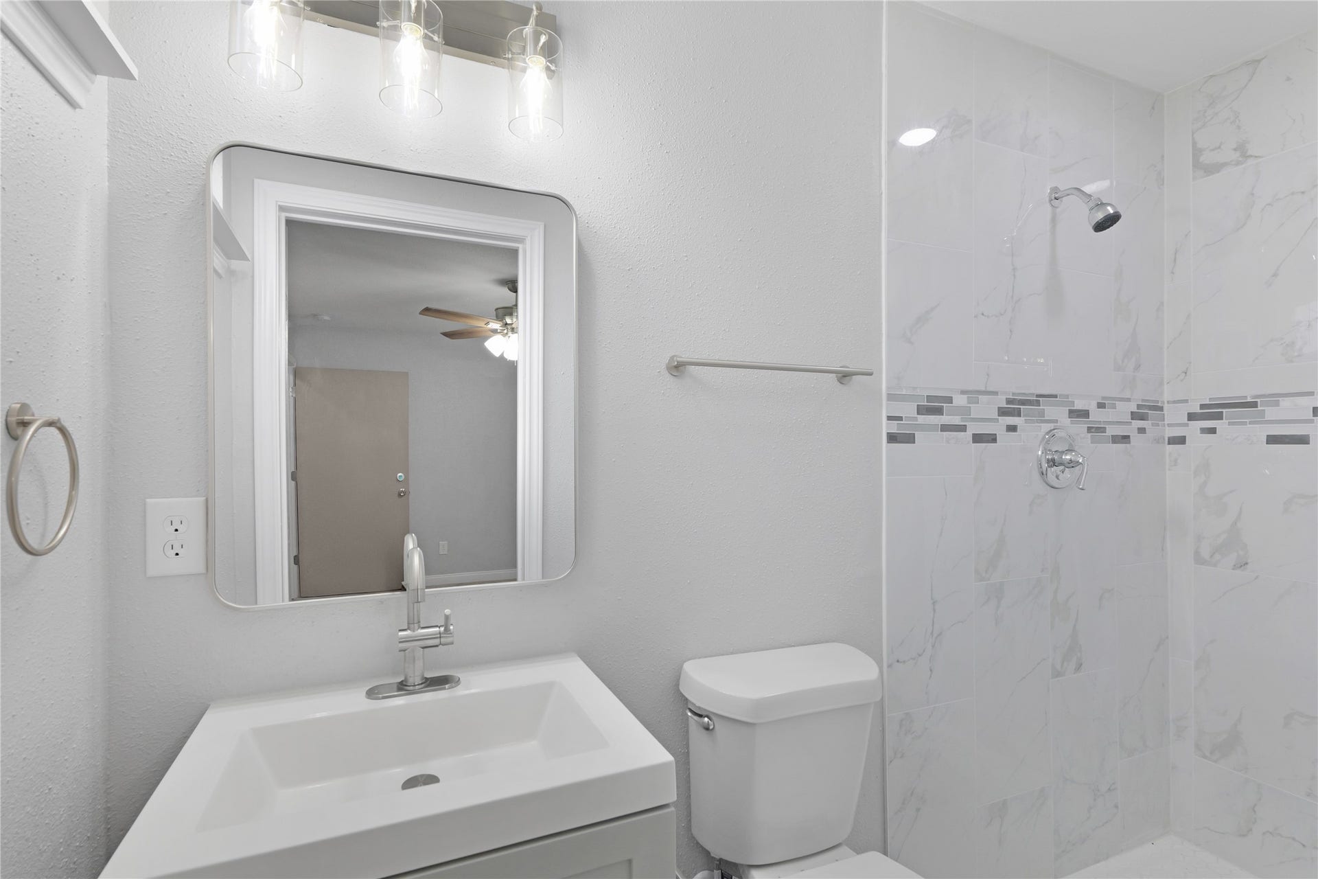 9827 Shive Drive, Houston, TX 77078 A tiled walk-in shower with a decorative accent pairs with an updated vanity and framed mirror.