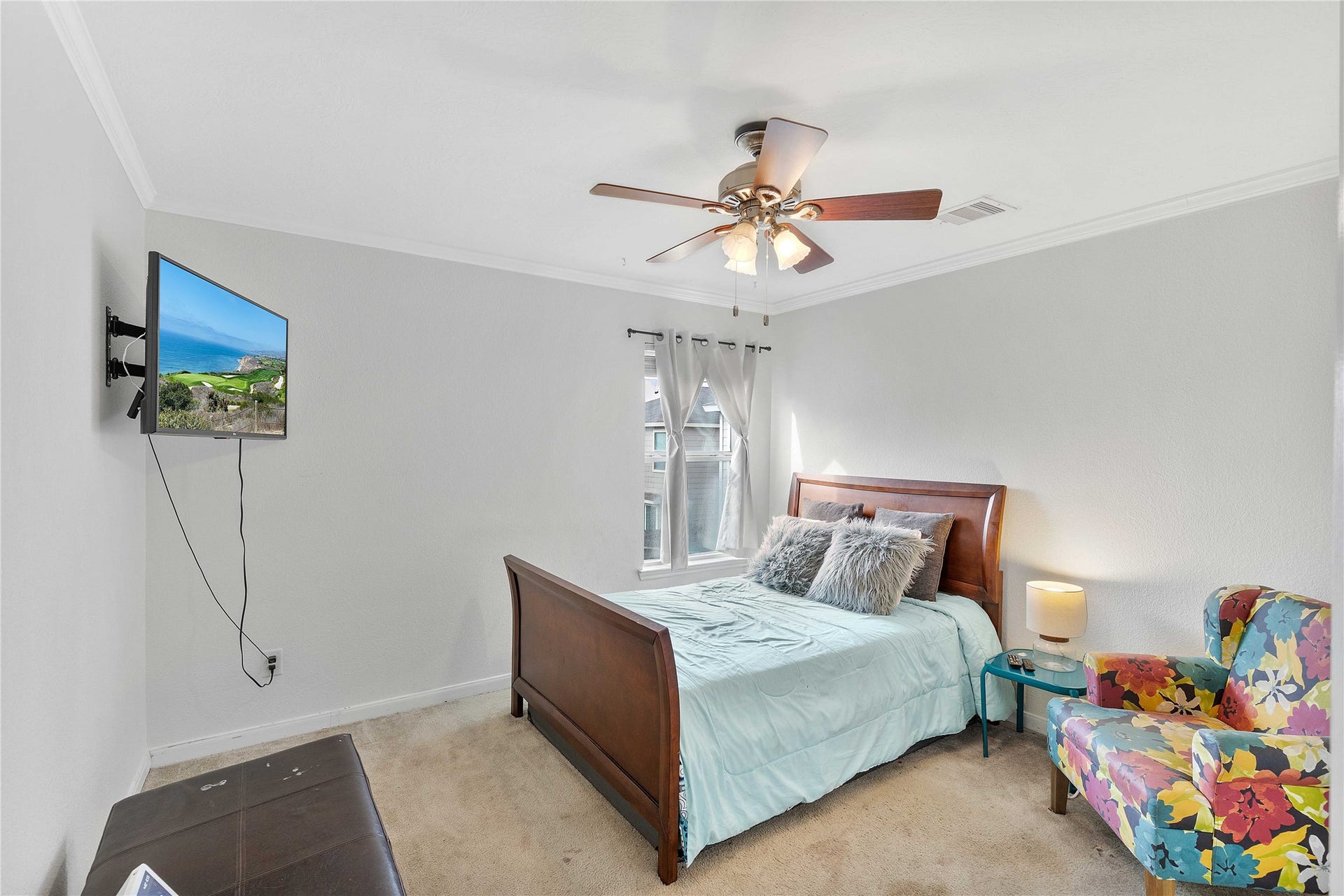 2910 Ribbon Creek Way, Spring, TX 77389 Cozy bedroom with a stylish ceiling fan, wall-mounted TV, and ample natural light. Features a comfortable bed with plush pillows and a colorful accent chair for added charm.