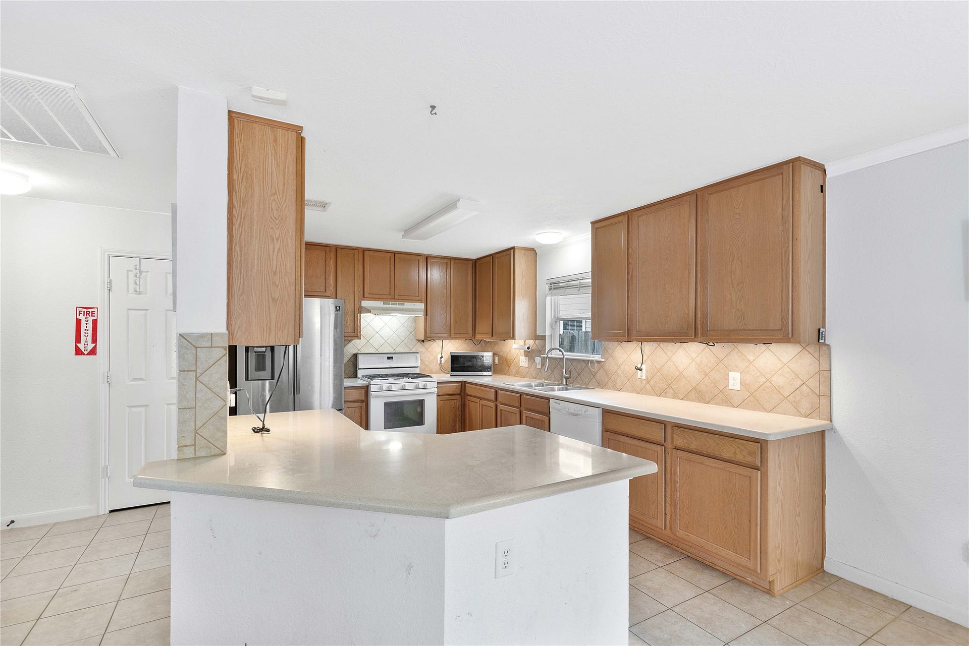 2910 Ribbon Creek Way, Spring, TX 77389 Spacious kitchen with abundant wood cabinetry, sleek countertops, and modern stainless steel appliances, complemented by a large island and tile flooring for easy maintenance.