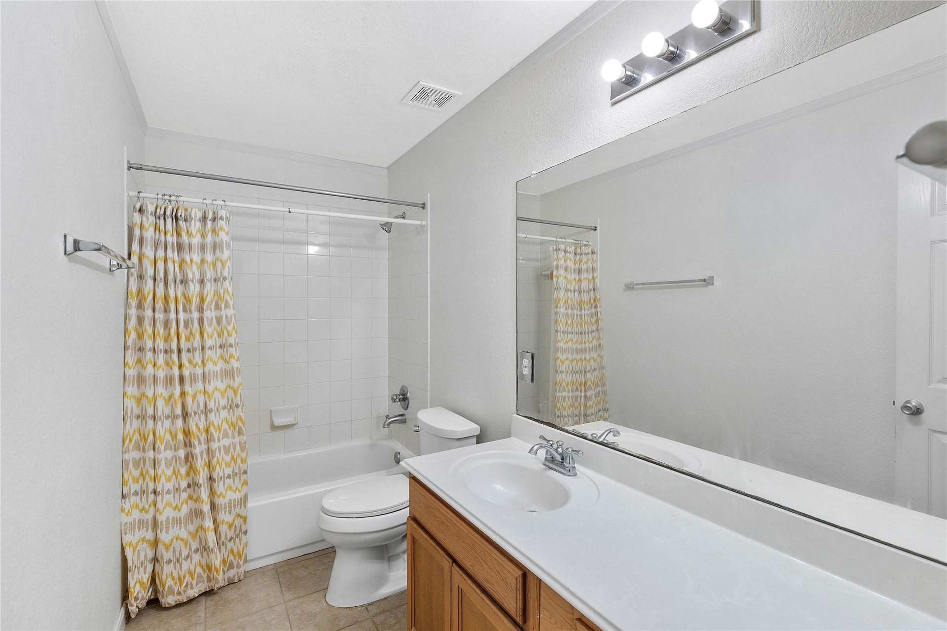 2910 Ribbon Creek Way, Spring, TX 77389 Bright bathroom featuring a spacious vanity, modern lighting, and a bathtub with a stylish patterned shower curtain.