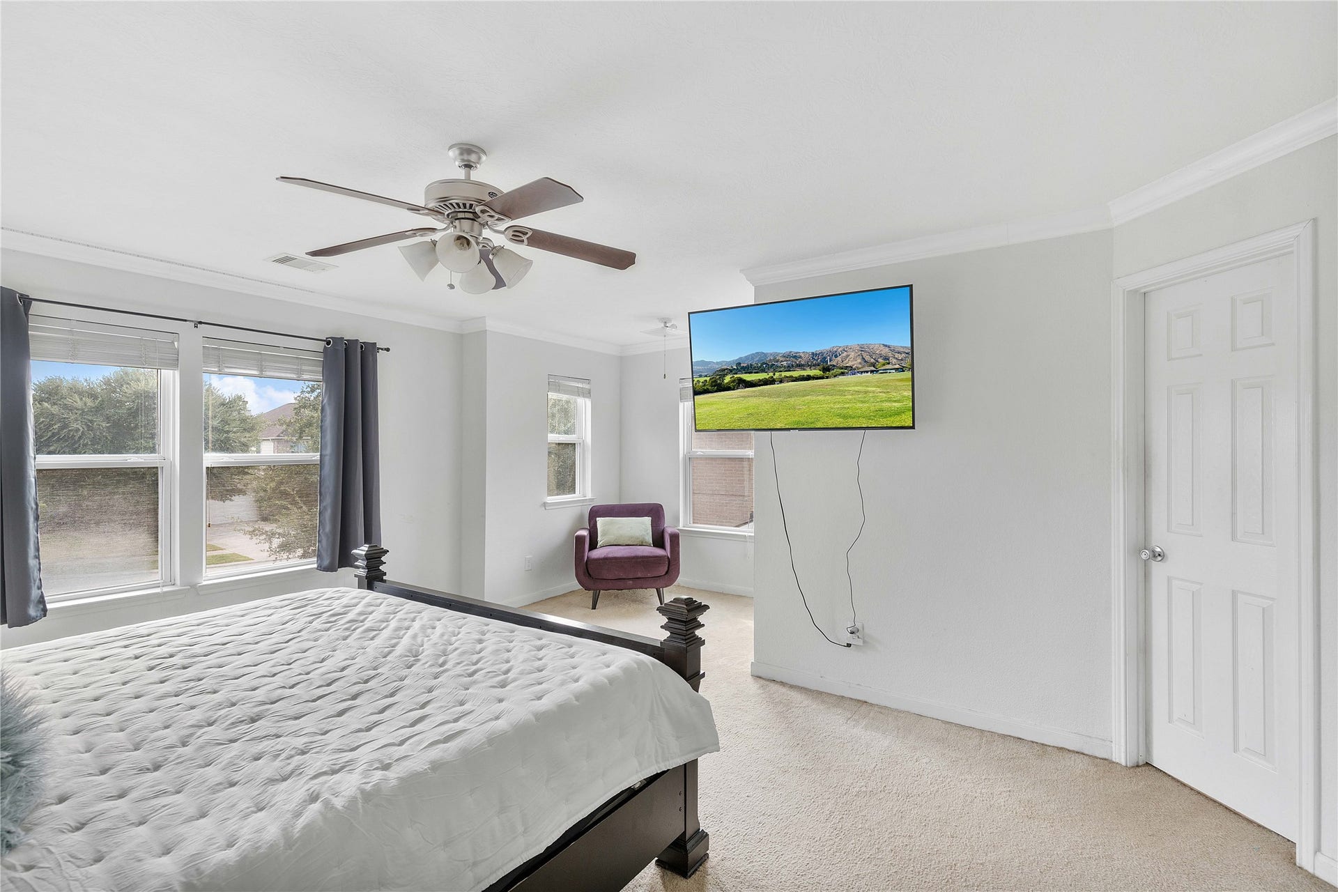 2910 Ribbon Creek Way, Spring, TX 77389 Spacious and bright bedroom with large windows, modern ceiling fan, and a wall-mounted TV, offering a cozy and inviting ambiance.
