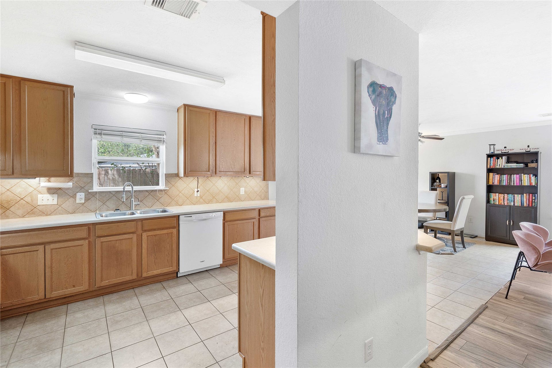 2910 Ribbon Creek Way, Spring, TX 77389 Bright kitchen with warm wood cabinetry and tiled backsplash, seamlessly flowing into a cozy living area featuring built-in shelving and modern seating.